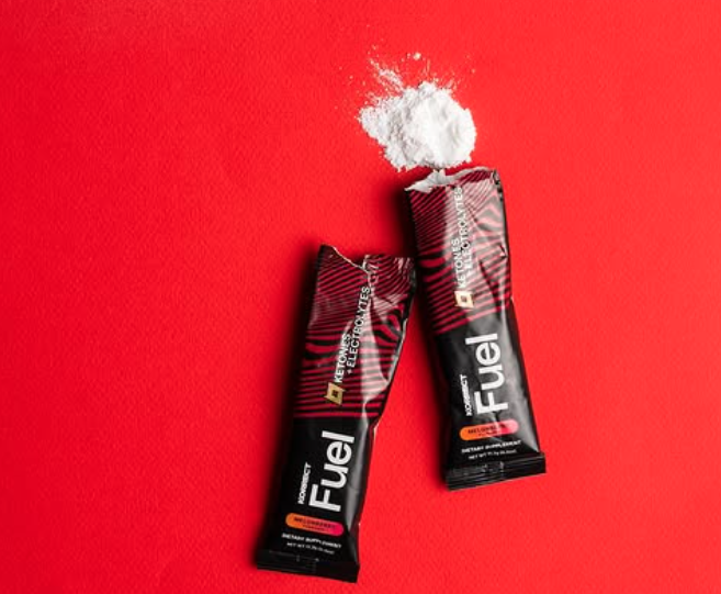 Korrect Fuel exogenous ketone powder packets with BHB supplement poured from single-serve stick on red background