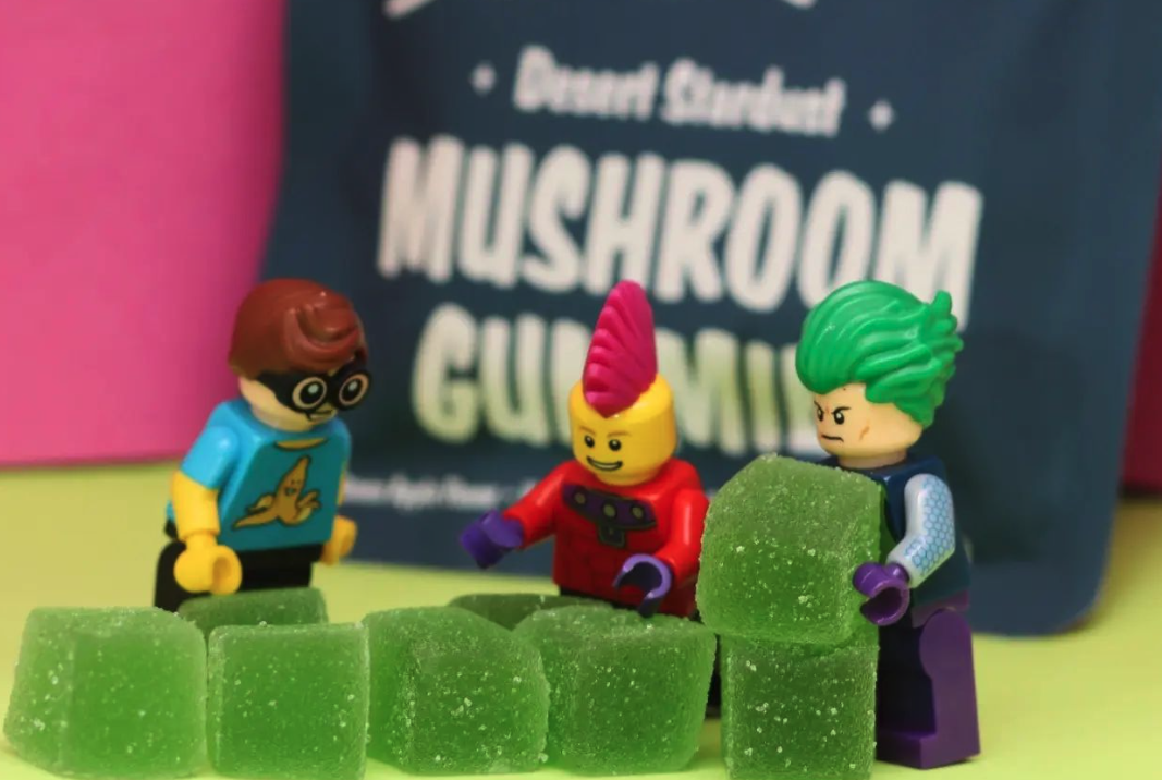 Pineapple flavor Road Trip mushroom gummy cubes lined up with the pouch in the background