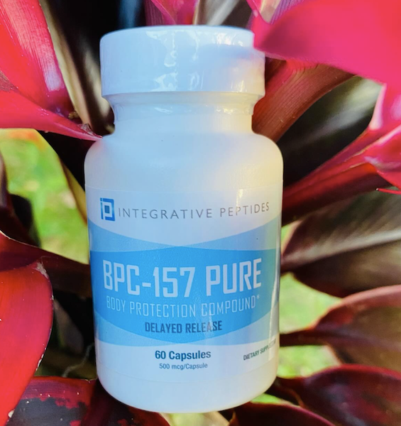 Integrative Peptides BPC-157 Pure delayed release capsule bottle styled against a tropical plant background