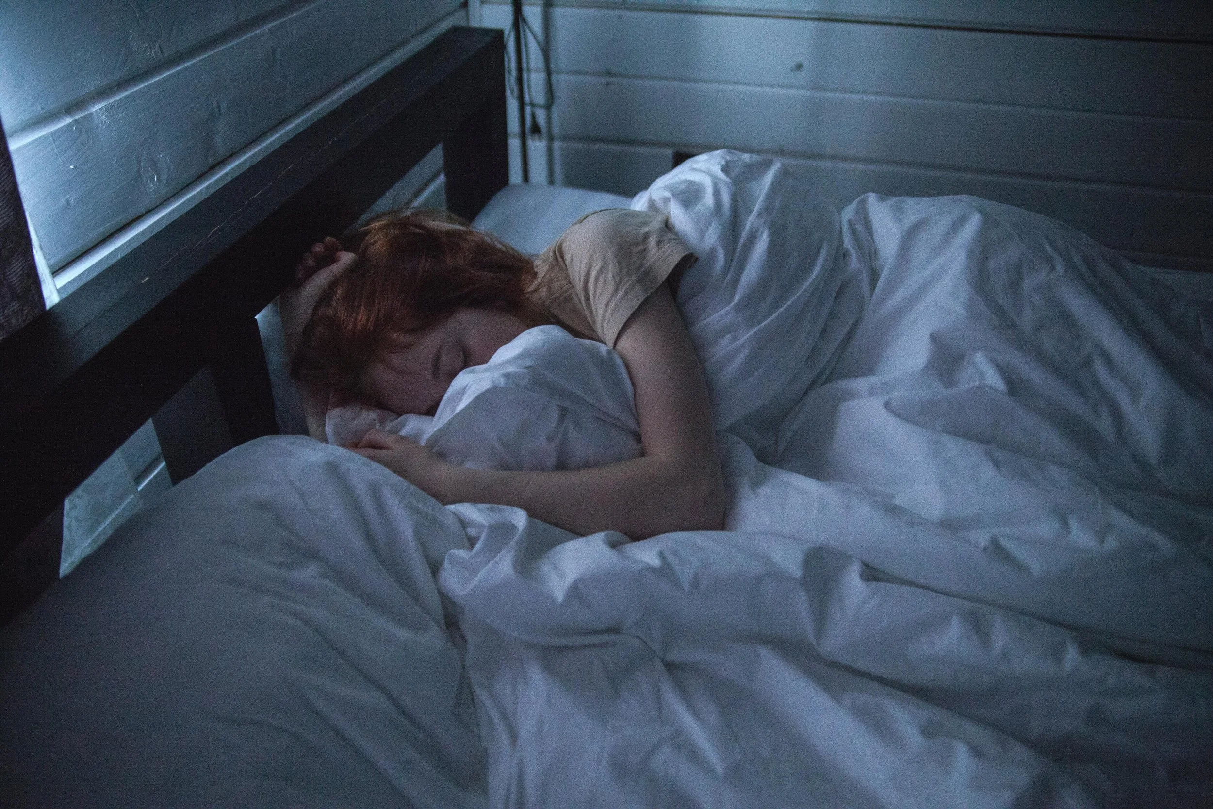 Person sleeping in a dark, cool bedroom