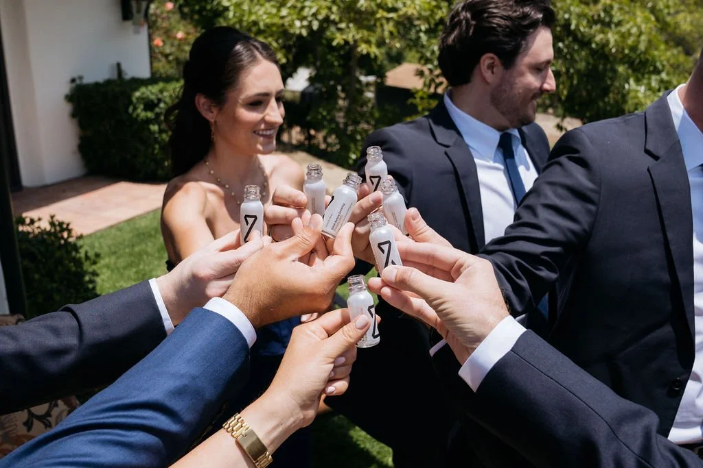 A group of friends toasting with ZBiotics Pre-Alcohol bottles before a wedding celebration