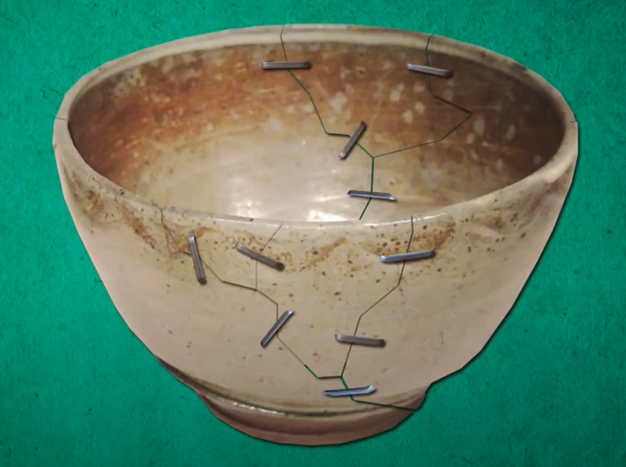 An older ceramic bowl repaired with metal staples drilled through the porcelain