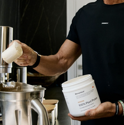 Momentous plant protein powder being scooped into mixer for muscle recovery strength and daily performance nutrition