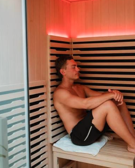 Man relaxing in an infrared sauna with red panel lighting