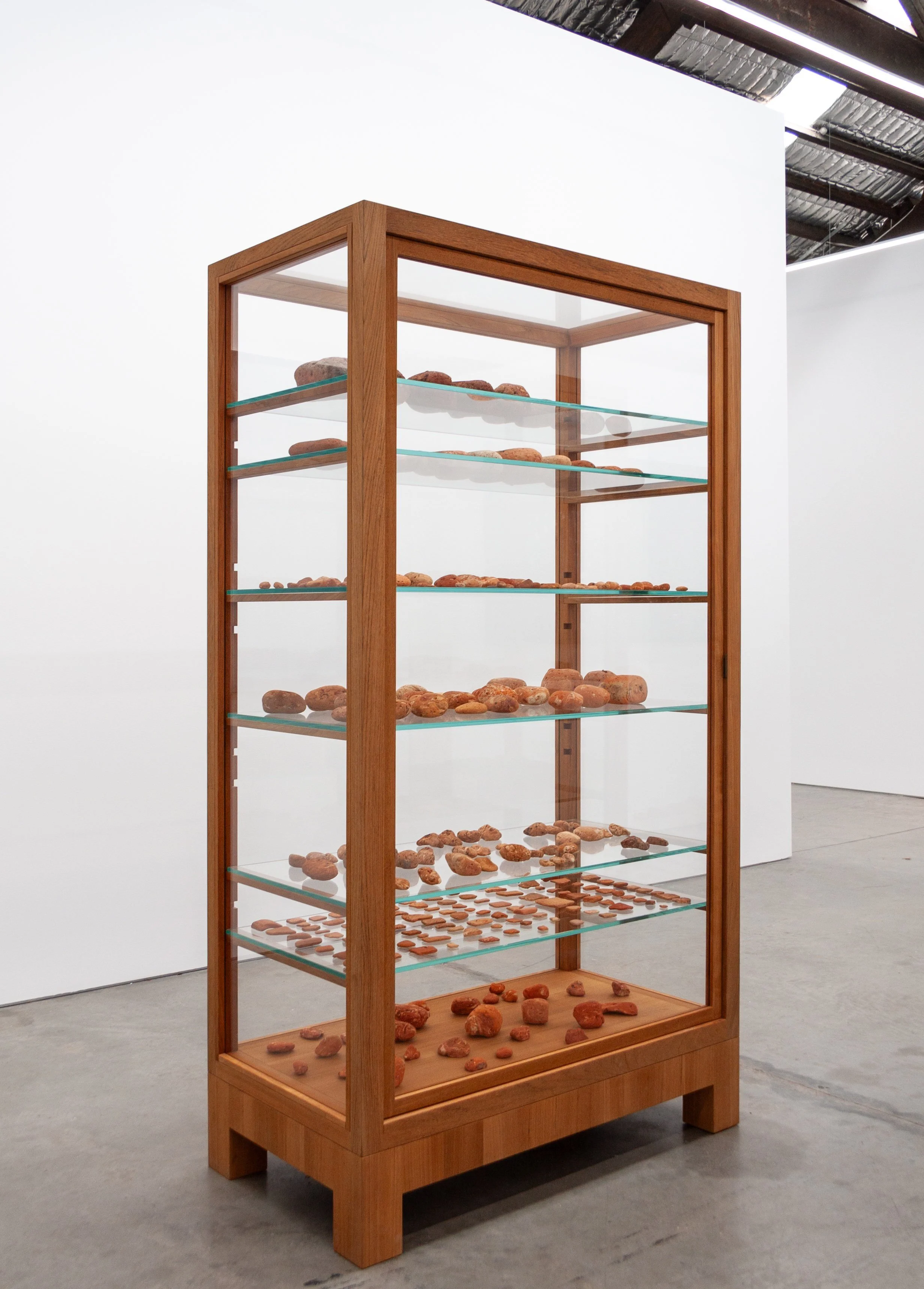 Simryn Gill, Domino Theory #2 (2014); Glass cabinet, sea worn brick; 78 x 41 x 22 inches; 199 x 105 x 56 cm
