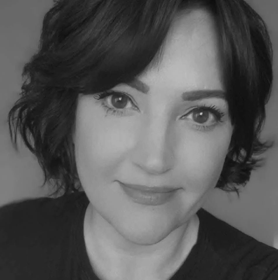 A black and white portrait of a woman with short, wavy hair, smiling gently at the camera.