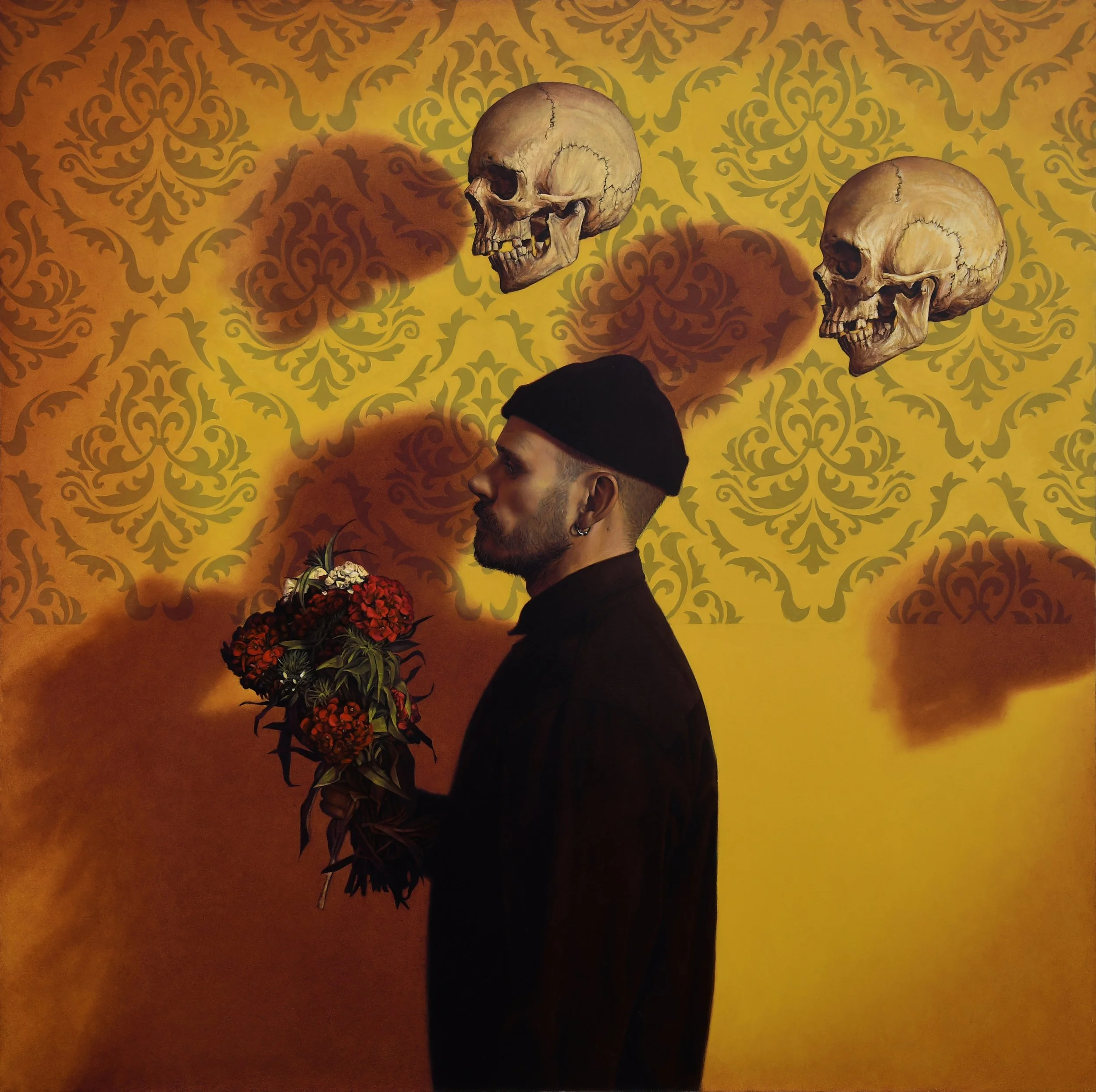 An oil painting of a man with a beard and earrings, wearing a black beanie and dark clothing, stands sideways holding a bouquet of red and white flowers against a yellow wall with ornate patterns. Three skulls are floating above him casting shadows.