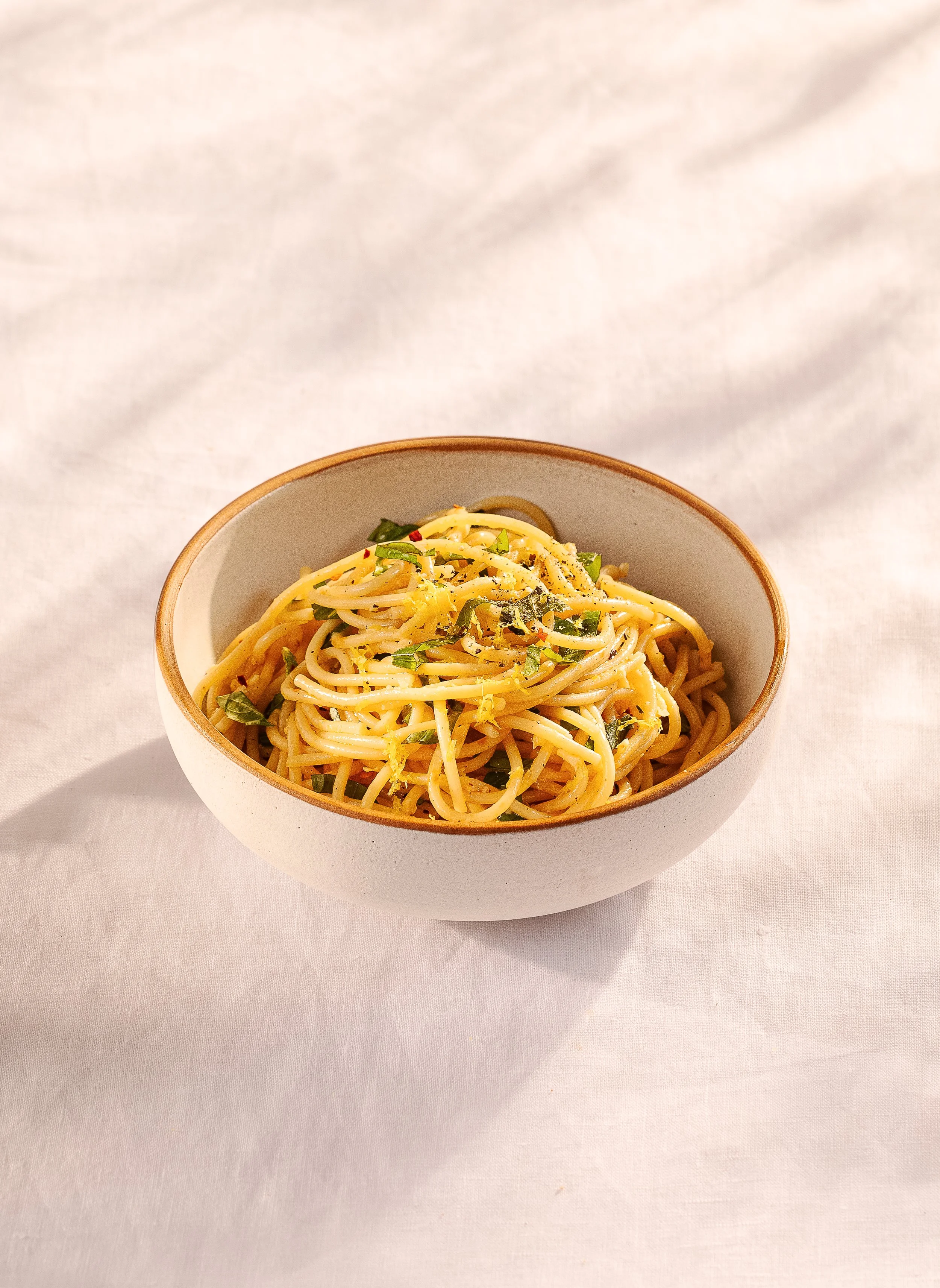 A bowl of spaghetti with herbs and pepper on a white surface from Food Photographer Glasgow
