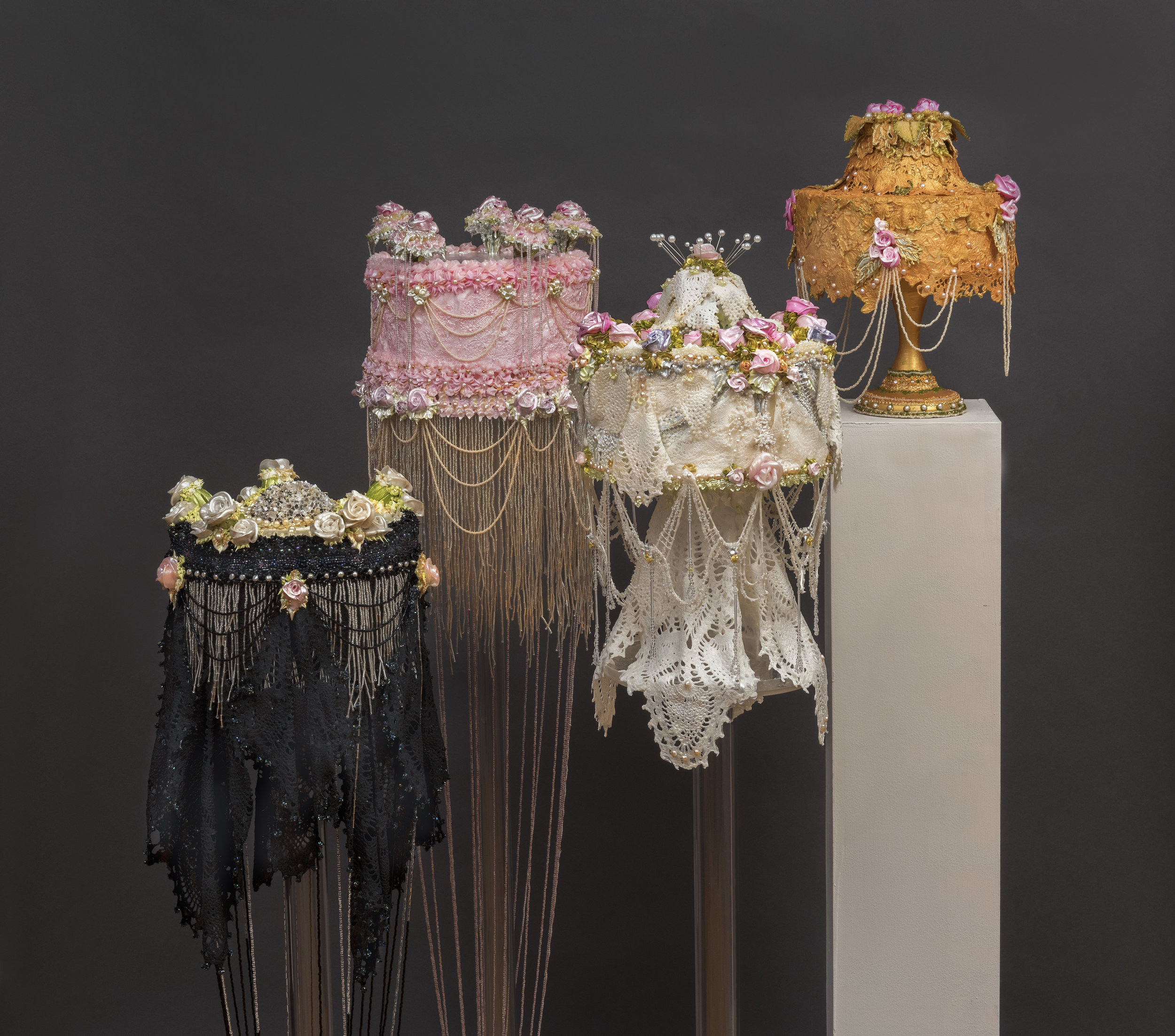 Four acrylic cakes (black, pink, white, orange) with pearls hanging