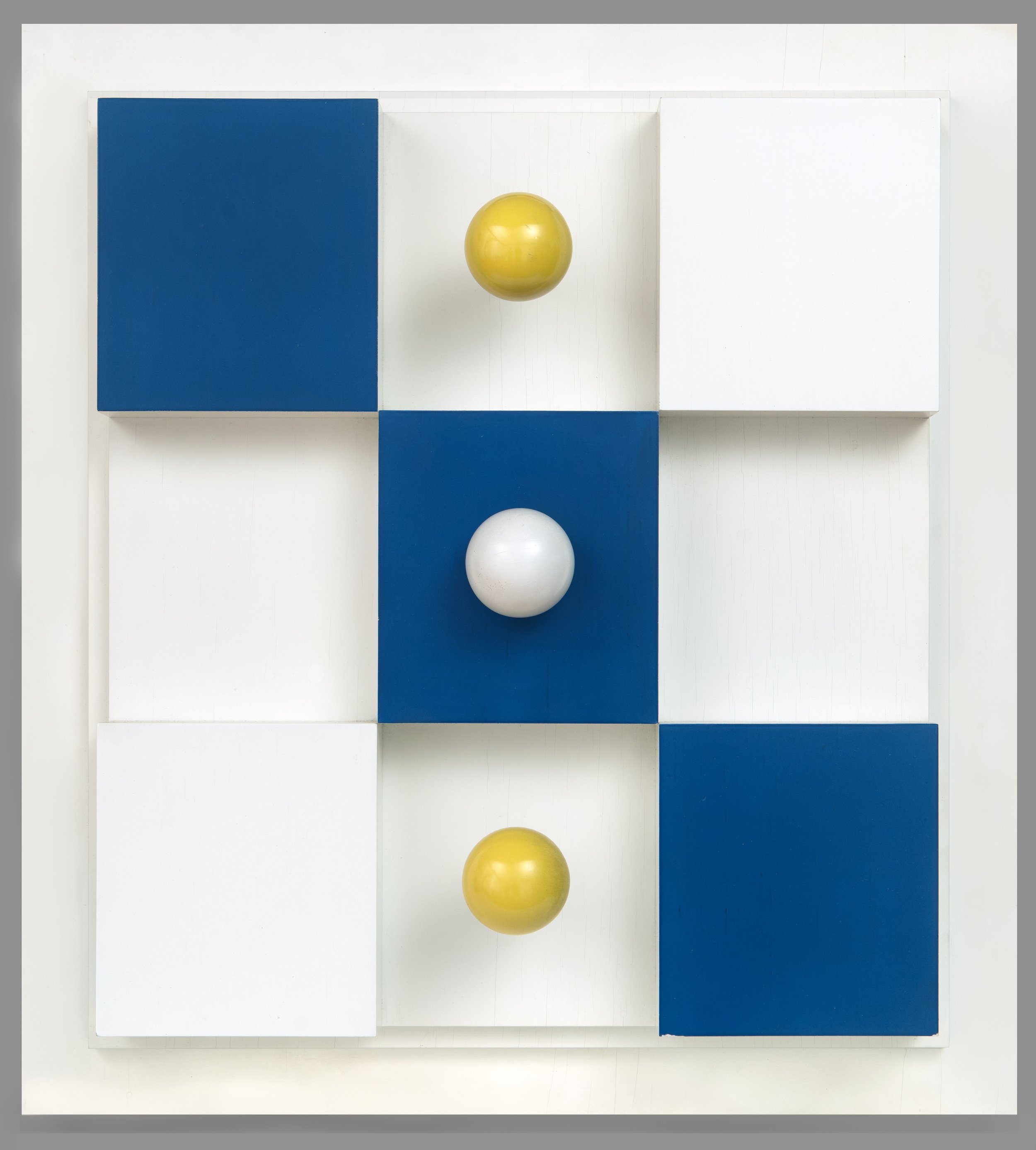 Geometric wood construction of cubes and spheres in white, blue, and yellow. 