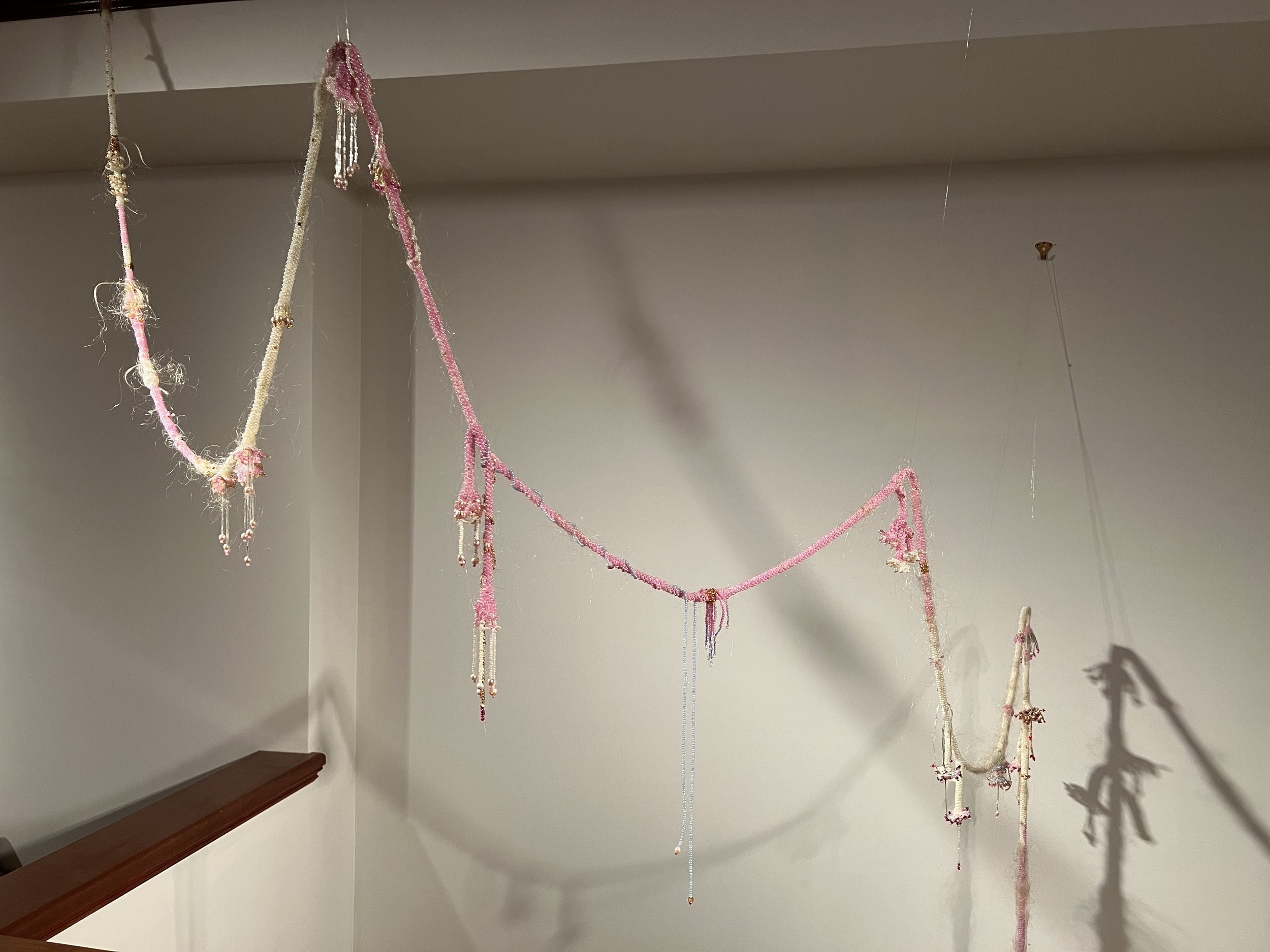 Installation of a pink and white bead and hairwork piece.
