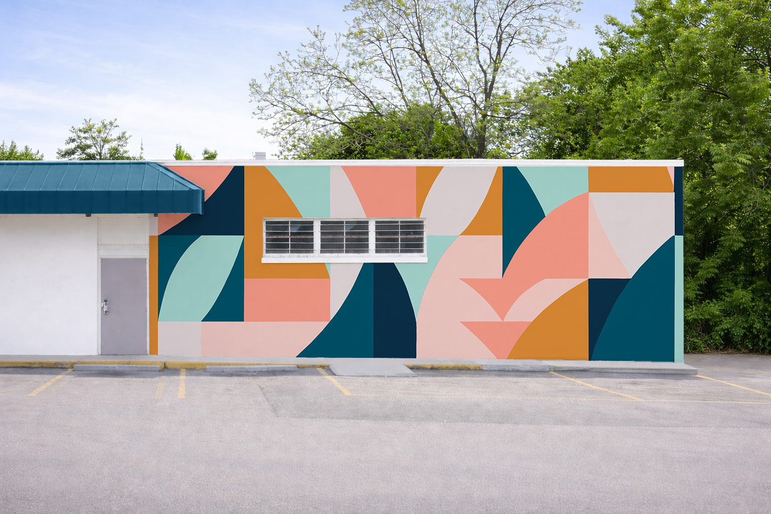 A building with a colorful abstract mural with geometric shapes in shades of blue, peach, white, and orange, and a blue awning over the entrance, surrounded by trees and a parking lot.