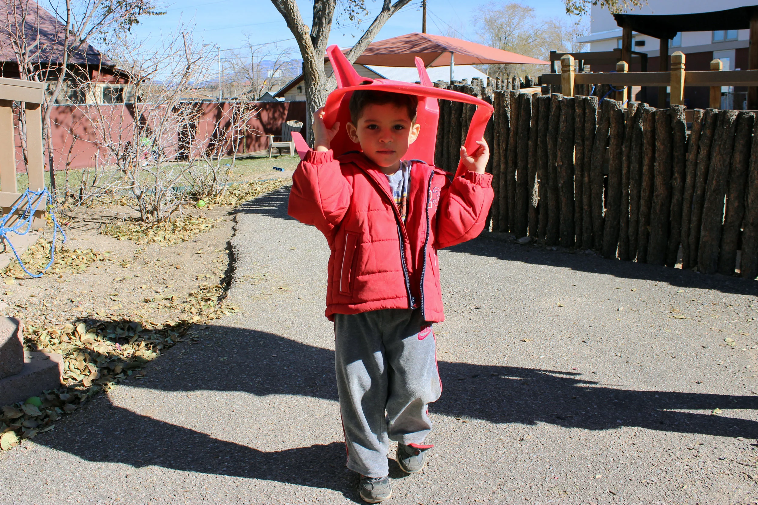 Emilio carries his chair through the courtyard at CLNKids on Nov. 26, 2014.