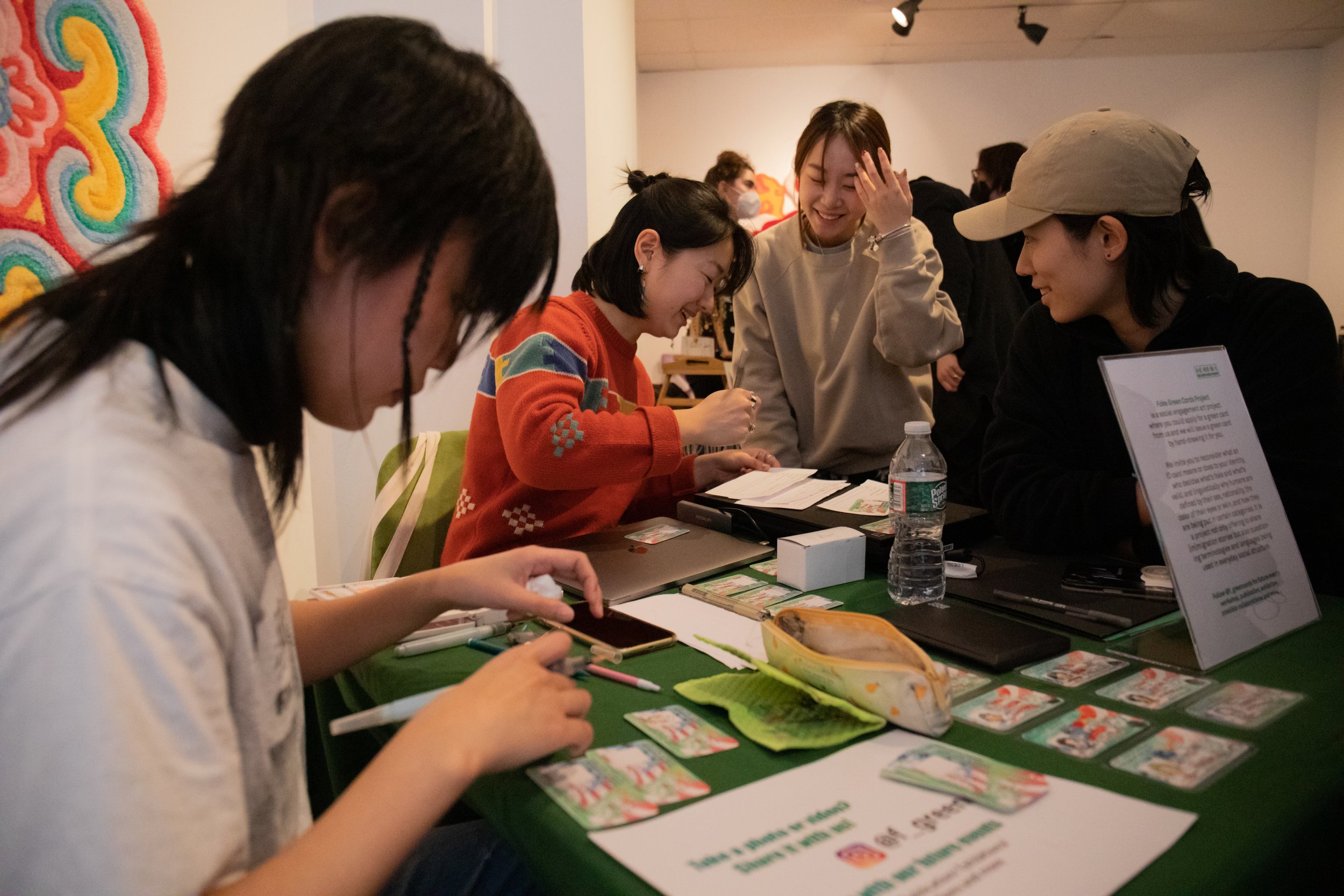  Xuan Liu left, draws participants while Youkun Zhou, middle, interacts, scans finished green cards and talks with participants Manman Li, middle right, and Ziyan Xin.  
