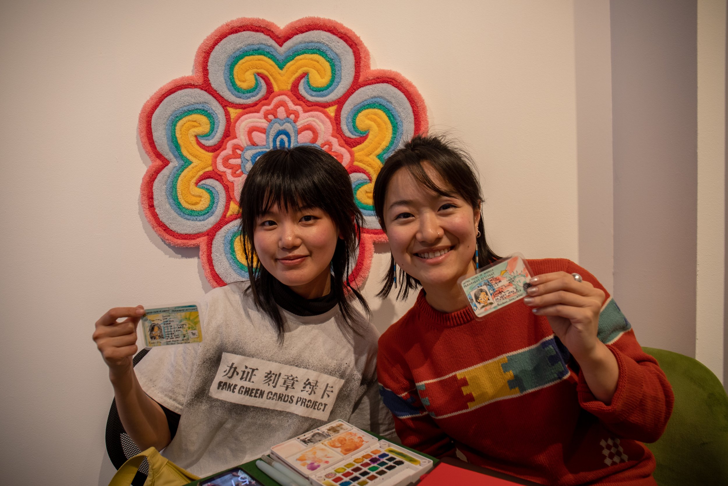  Xuan Liu, left, and Youkun Zhou with their personal fake green cards at the fair. 
