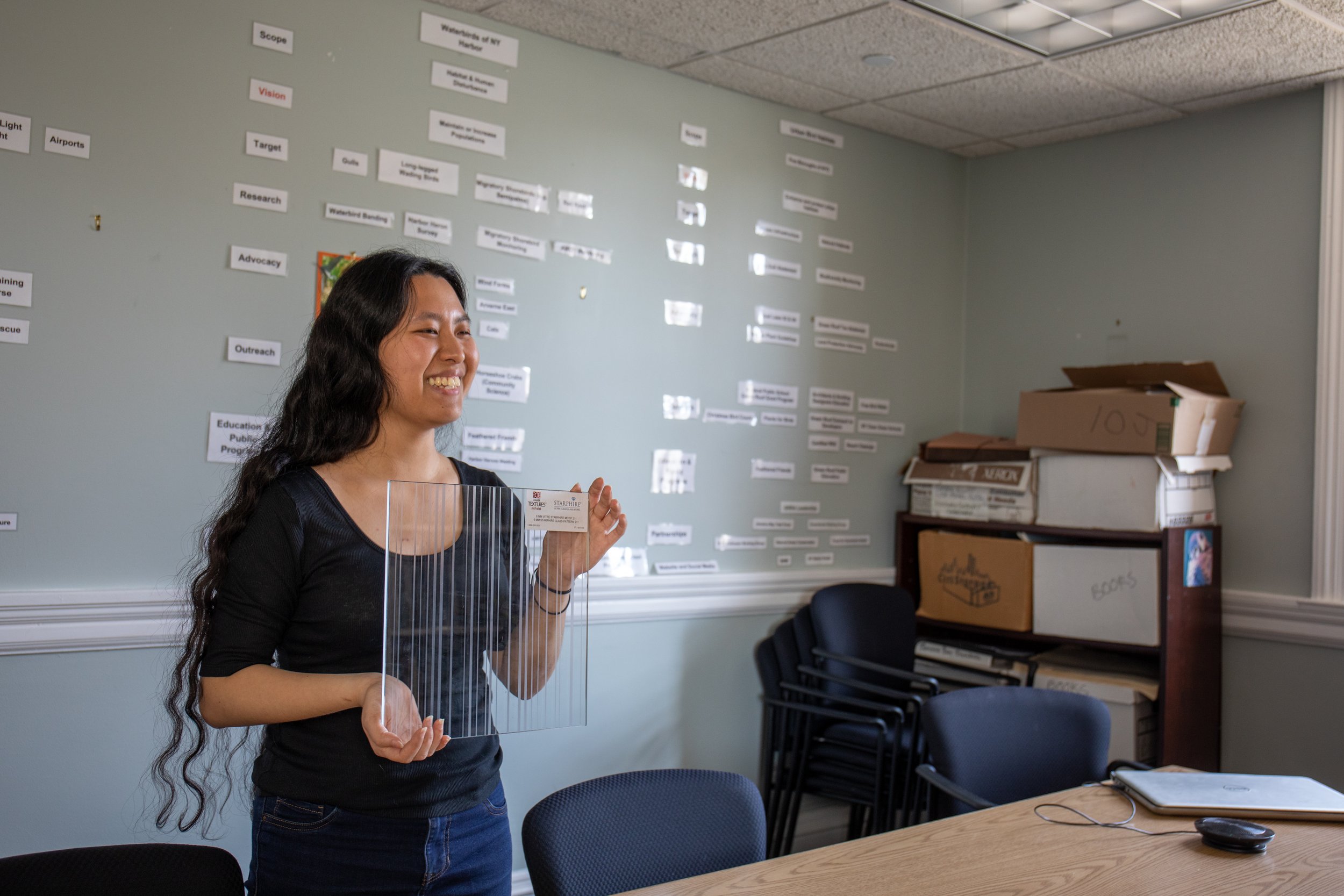  Chen holds a bird friendly piece of glass to demonstrate how its design helps prevent bird collisions during a visit to the New York City Audubon office Tuesday May 16. Bird-friendly glass is a great way to help migratory birds making their way thro