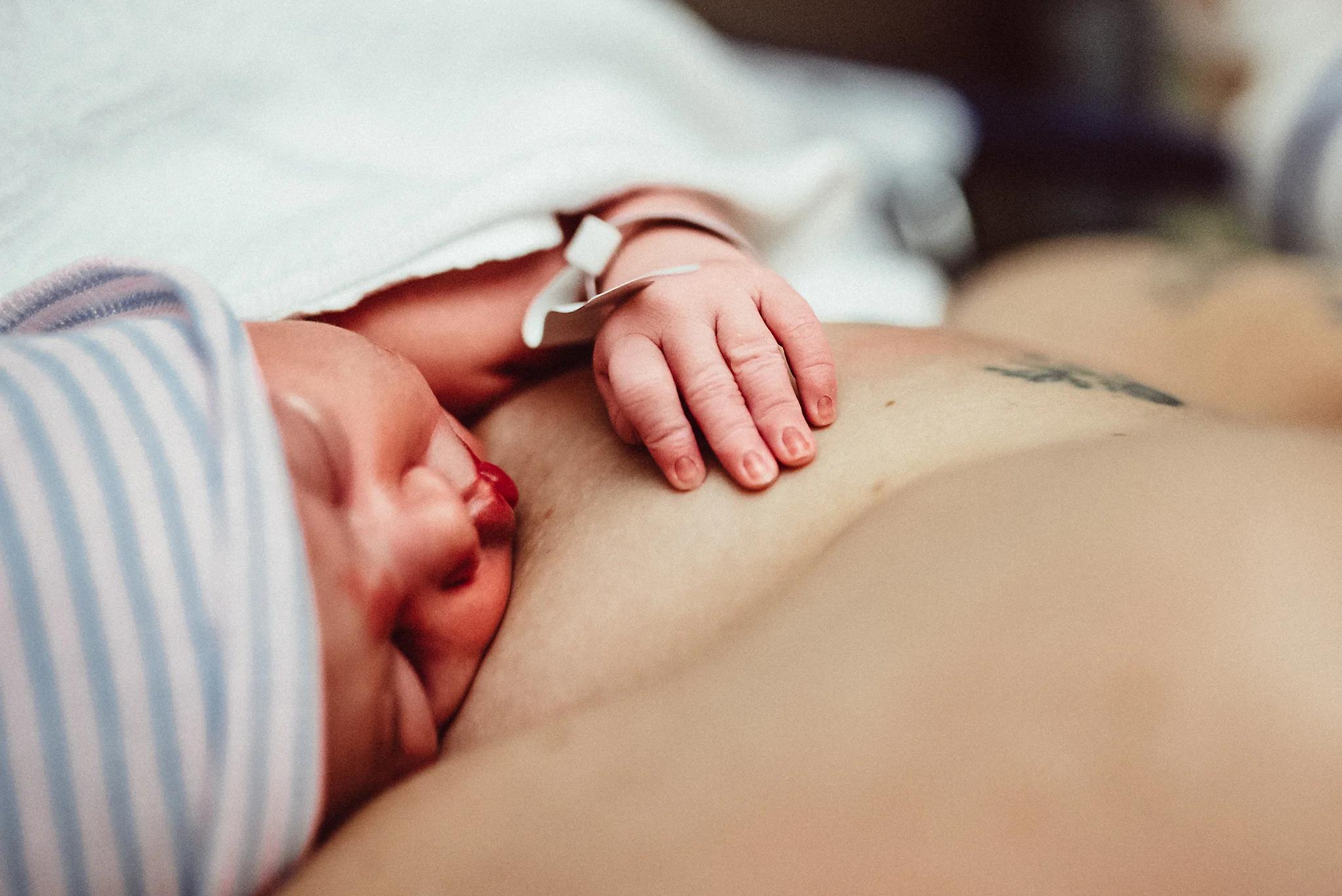 newborn face and fingers on mama's breast