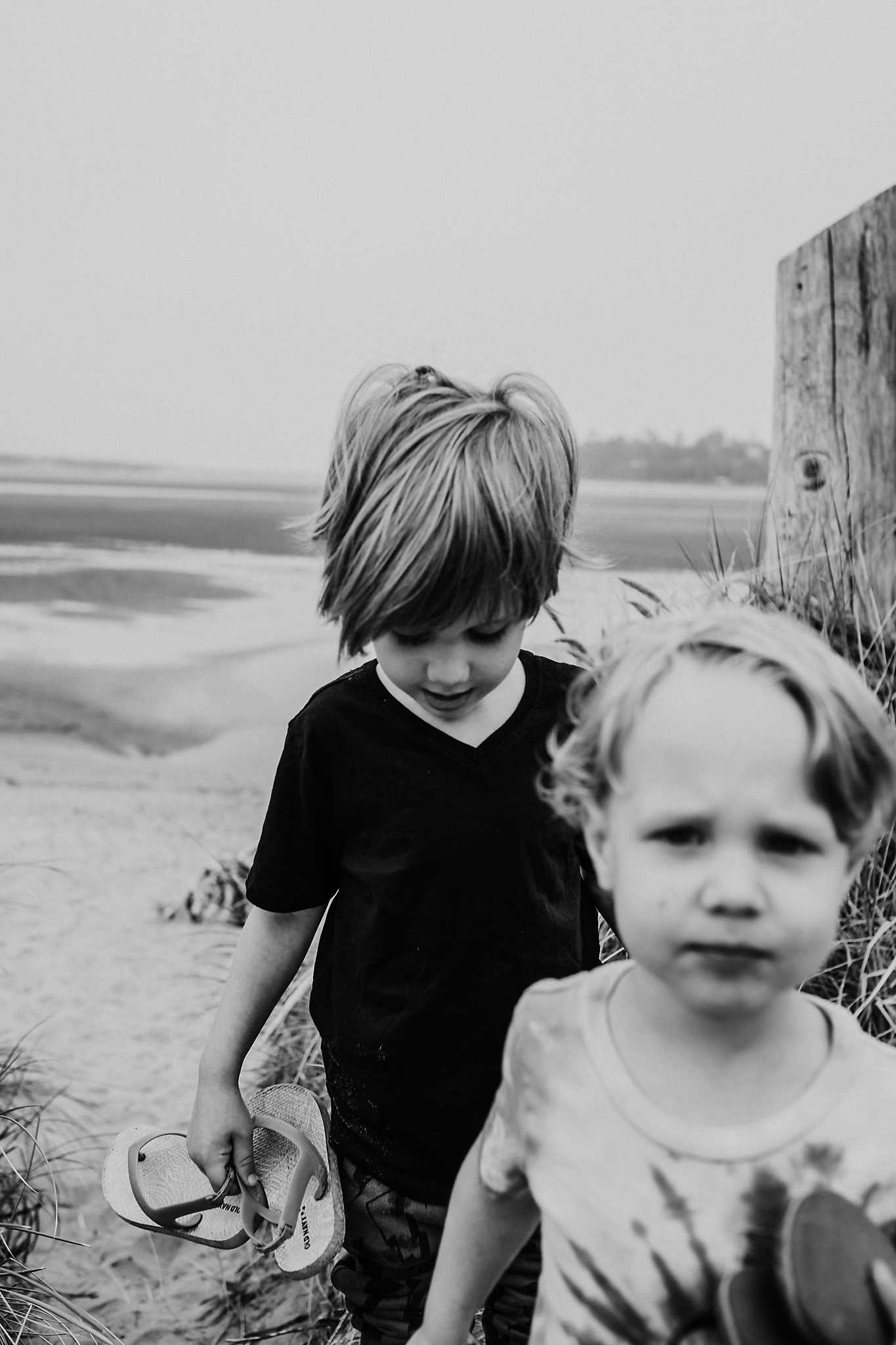 Boys at beach holding sandals