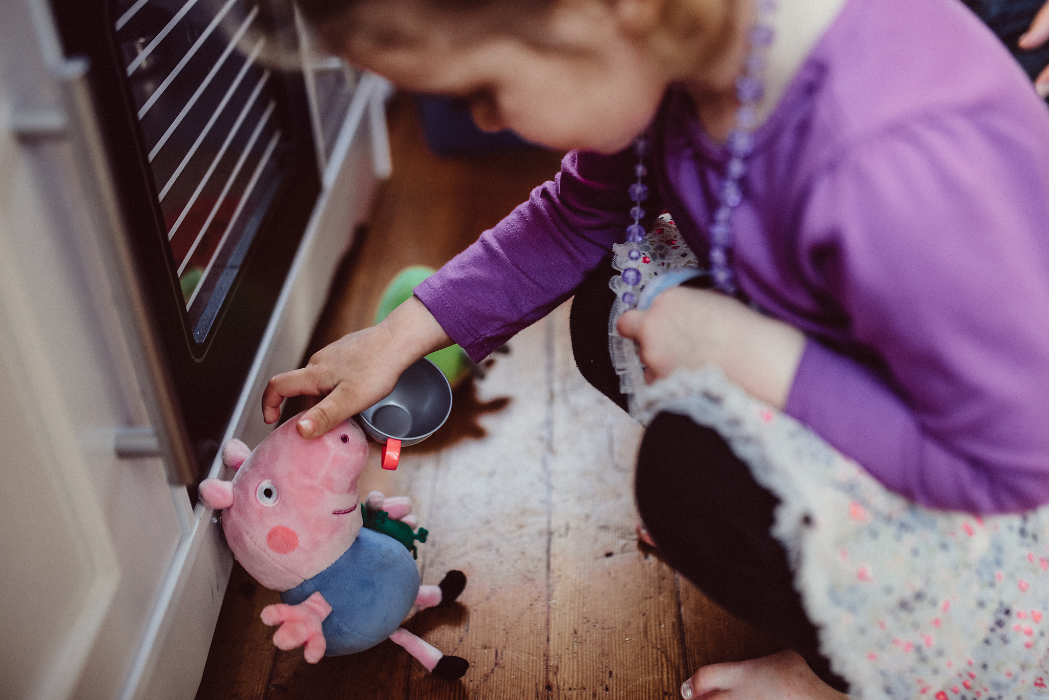Little girl playing with stuffed pig in kitchen play room