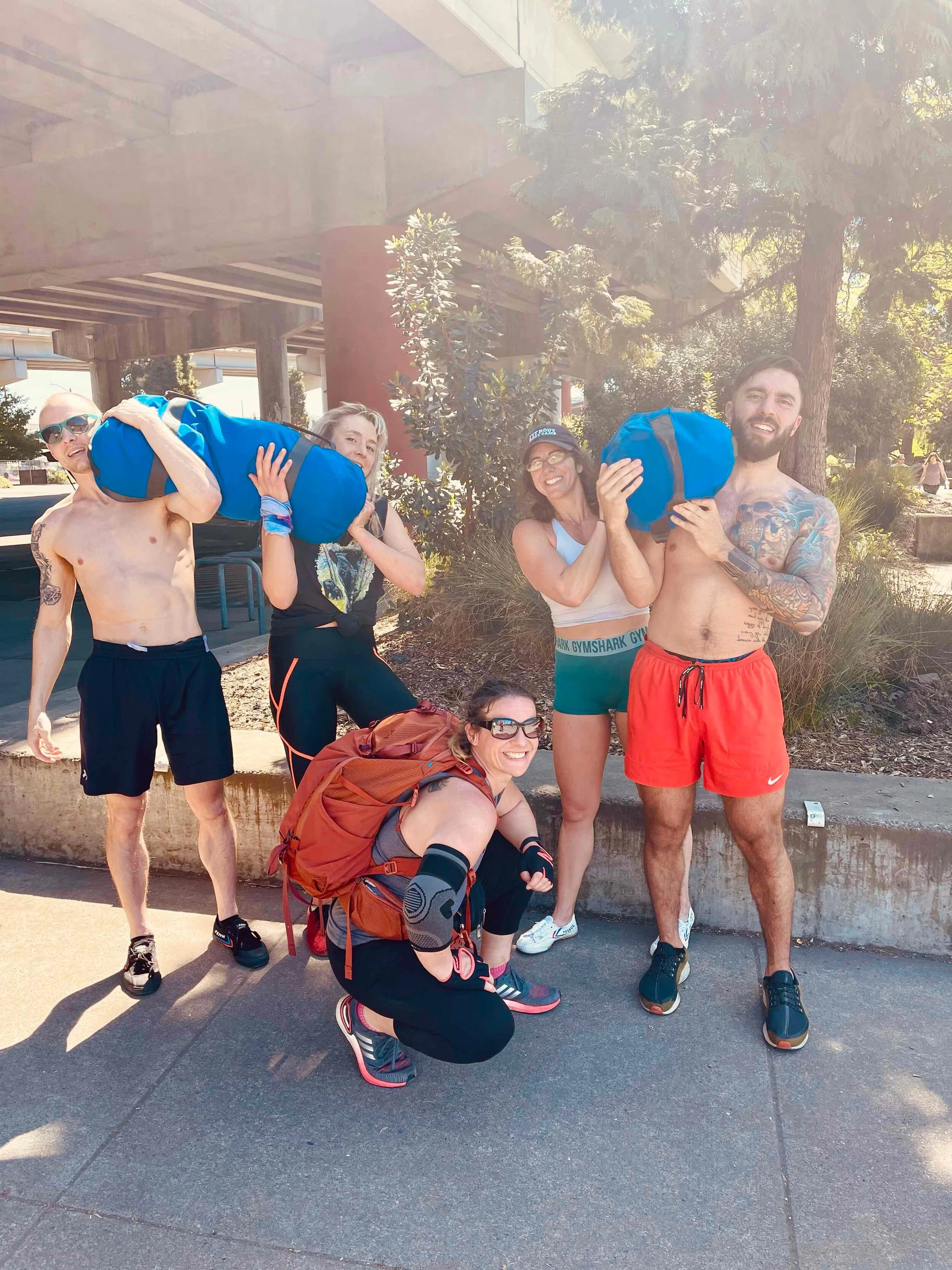  Fit Body Boot Camp owner Emily Johnson (green shorts) along with fitness and nutritional coaches (L to R) Dillon, Amanda, Julia and Brennon, part way through their team building event on April 17. They carried 150 lb. sand bags for two miles, circling the waterfront. Image Courtesy: Emily Johnson 