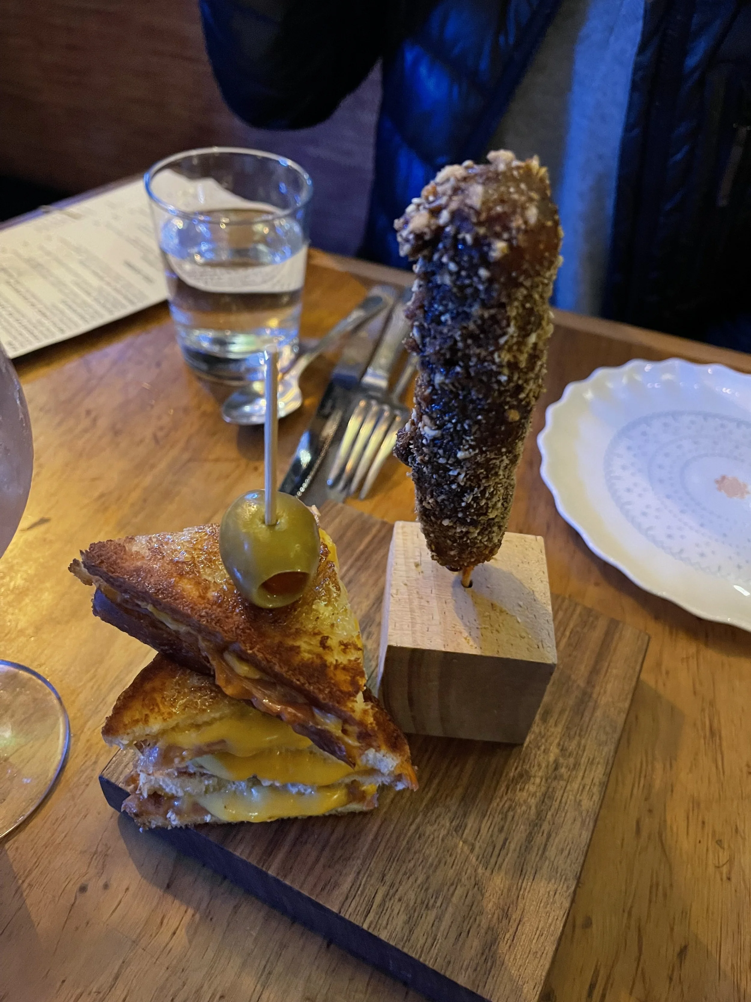 Looks a bit like a grilled cheese sandwich and a salted corn dog, right? Well…that’s kind of like comparing a bicycle to a Ferrari. Picture here from left to right are the “Bikini,” which is made up of jamon Serrano, American cheese, sofrito béchamel, toasted brioche and truffle honey, and then the “Bunuelo de Txistorra,” which is composed of house-made Basque chorizo, Estrella tempura, molasses, and corn nuts. So outstanding both of these! Image Courtesy: Dan Meyers