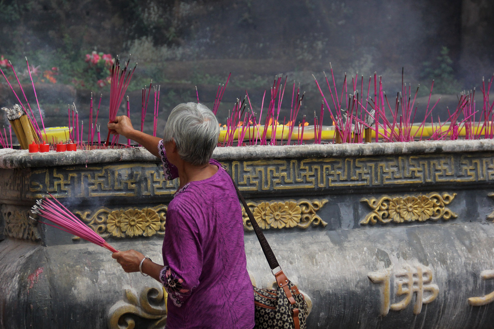 Woman praying at the foot of the Giant Buddha. The purple and pink colors!