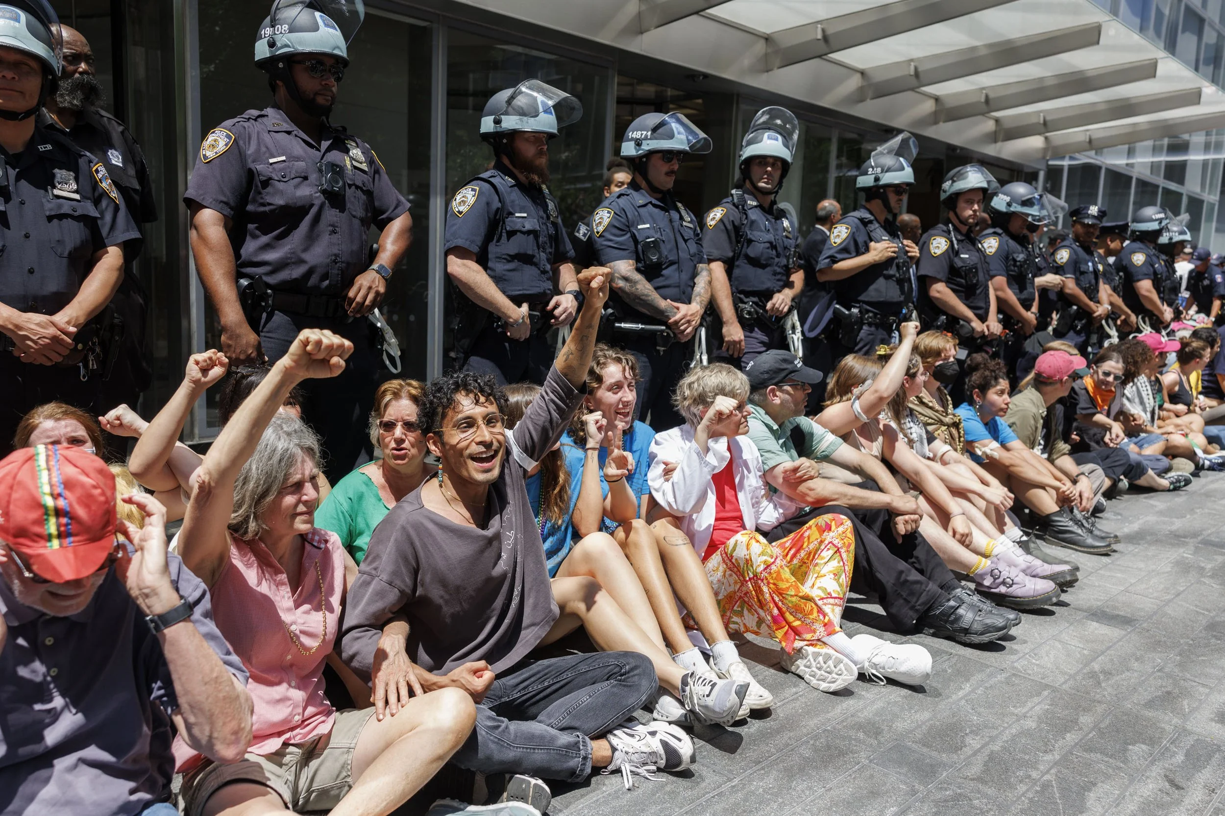  People part of the “Summer of Heat on Wall Street” protest group lock arms in front of police officers as an act of "non-violent civil disobedience" at Citigroup Headquarters in New York, New York, 28 June 2024. The group was joined by about 200 peo