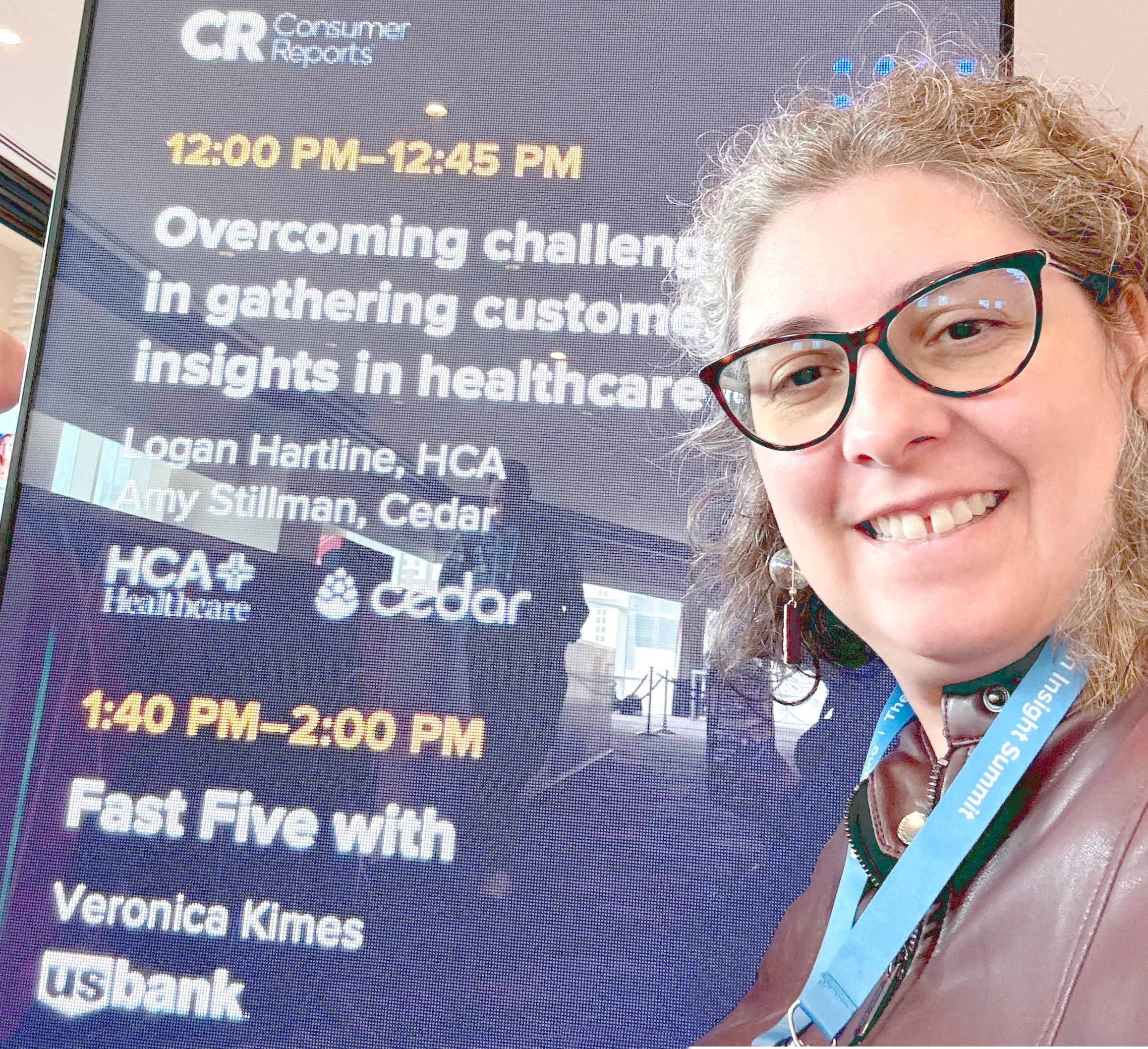Veronica with the Speaking engagement schedule board, showing her "Fast Five" time slot at the 2025 Human insight Summit (THiS)