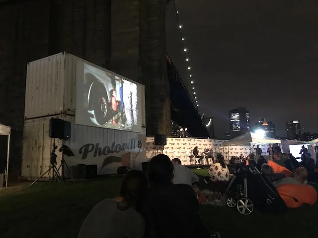 At Friday’s nighttime event in the Photoville beer garden, Getty Images Special Correspondent John Moore talked about his experiences documnenting U.S. immigration and border enforcement for a decade. The screen displays a well-known image taken by John of a crying 2-year-old girl who looked on as her mother was searched by U.S. Border Patrol agents in a part of the Rio Grande Valley called El Rincon.
