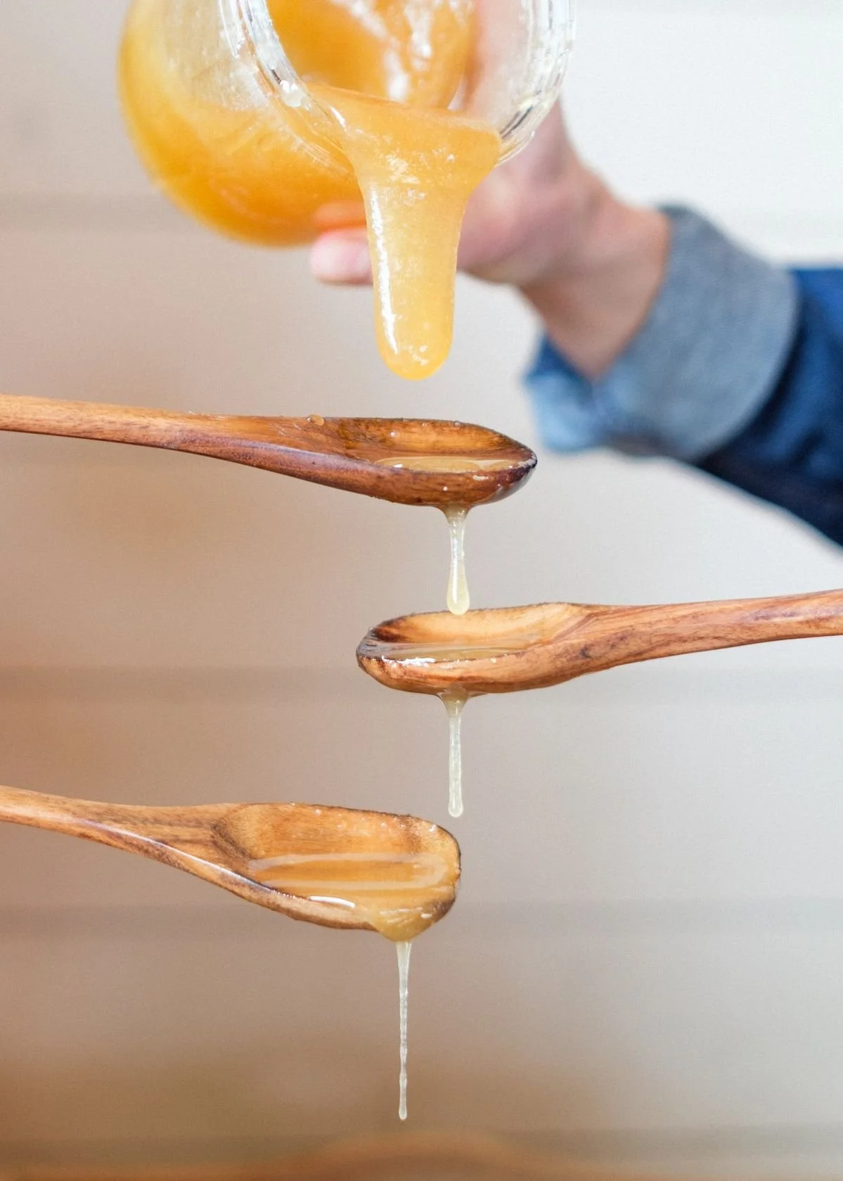 raw thick honey being poured into spoon in natural light