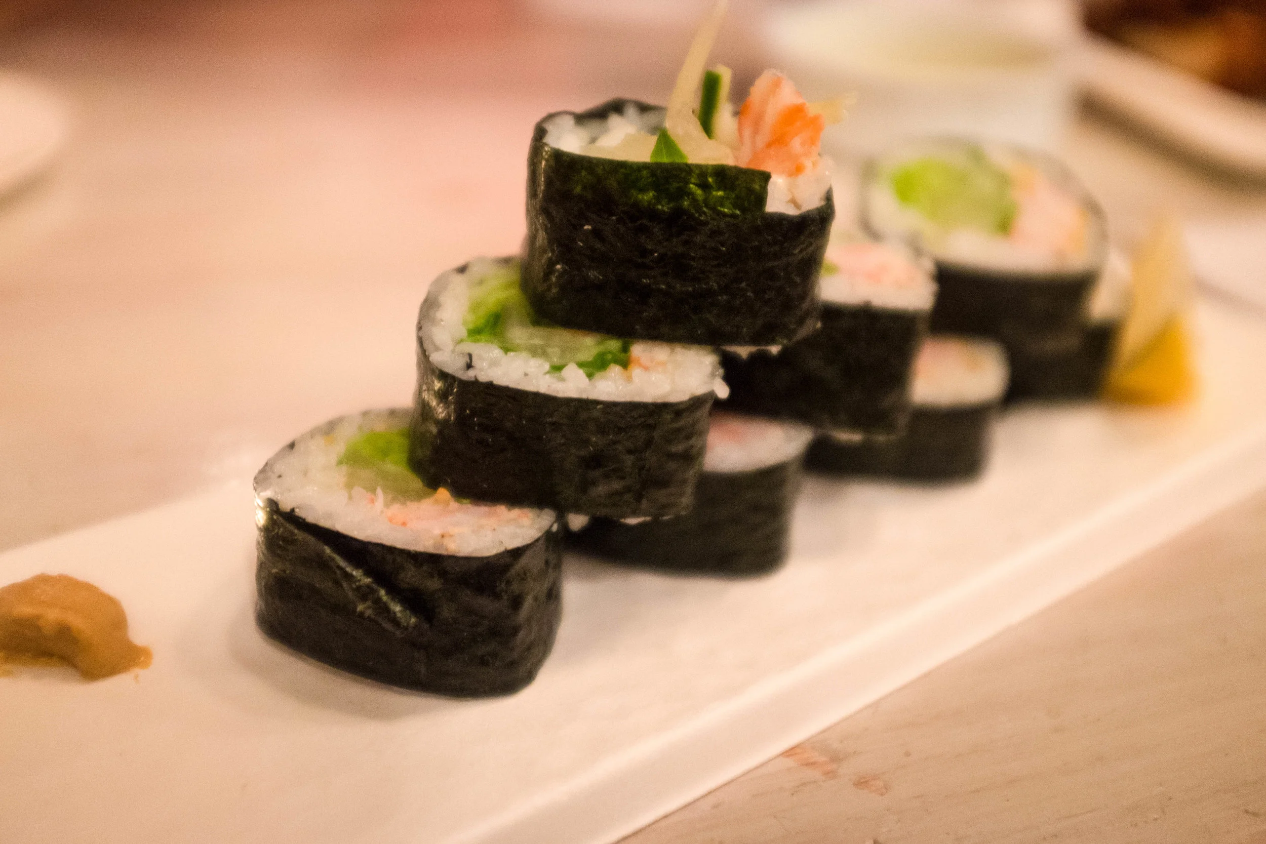 A shrimp and avocado sushi roll for the pescatarian of the group. It is sitting on top of a biodegrable serving platter. 