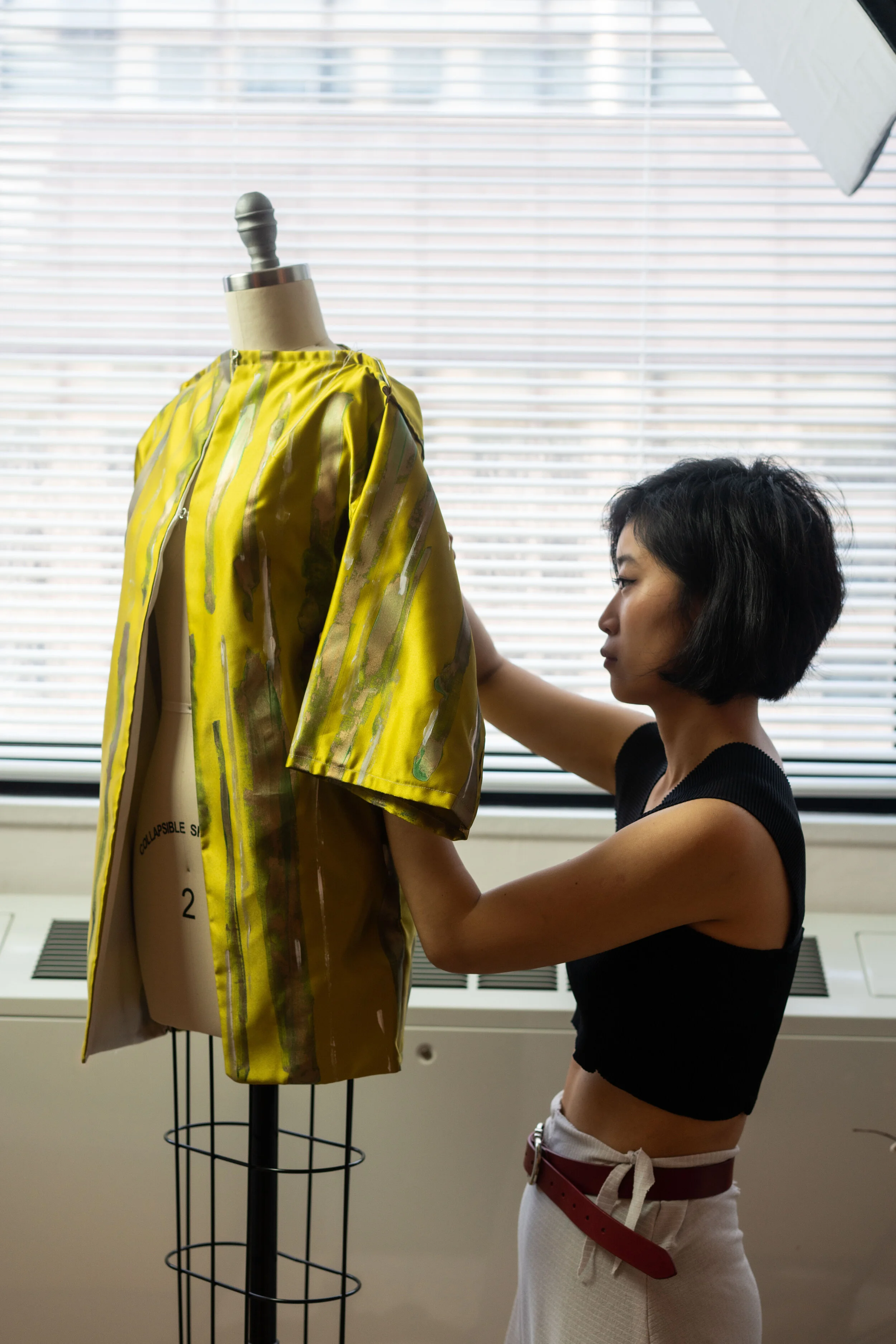 Xu in her studio making adjustments to one of her current pieces, featuring straight lines more aesthetically similar to the Japanese kimono, which much of zero-waste technique is based on.