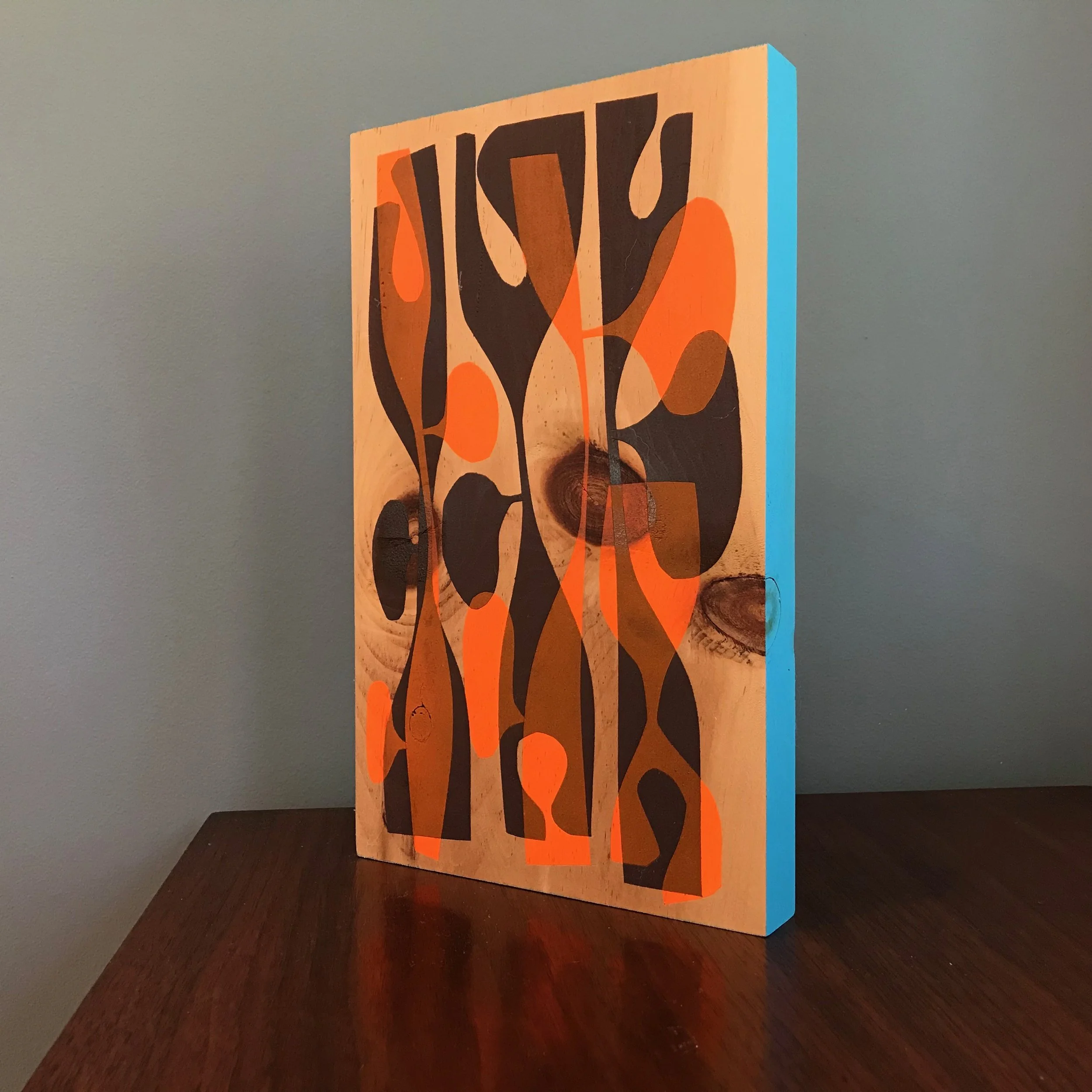 large painting with black and neon orange shapes with cyan blue edge