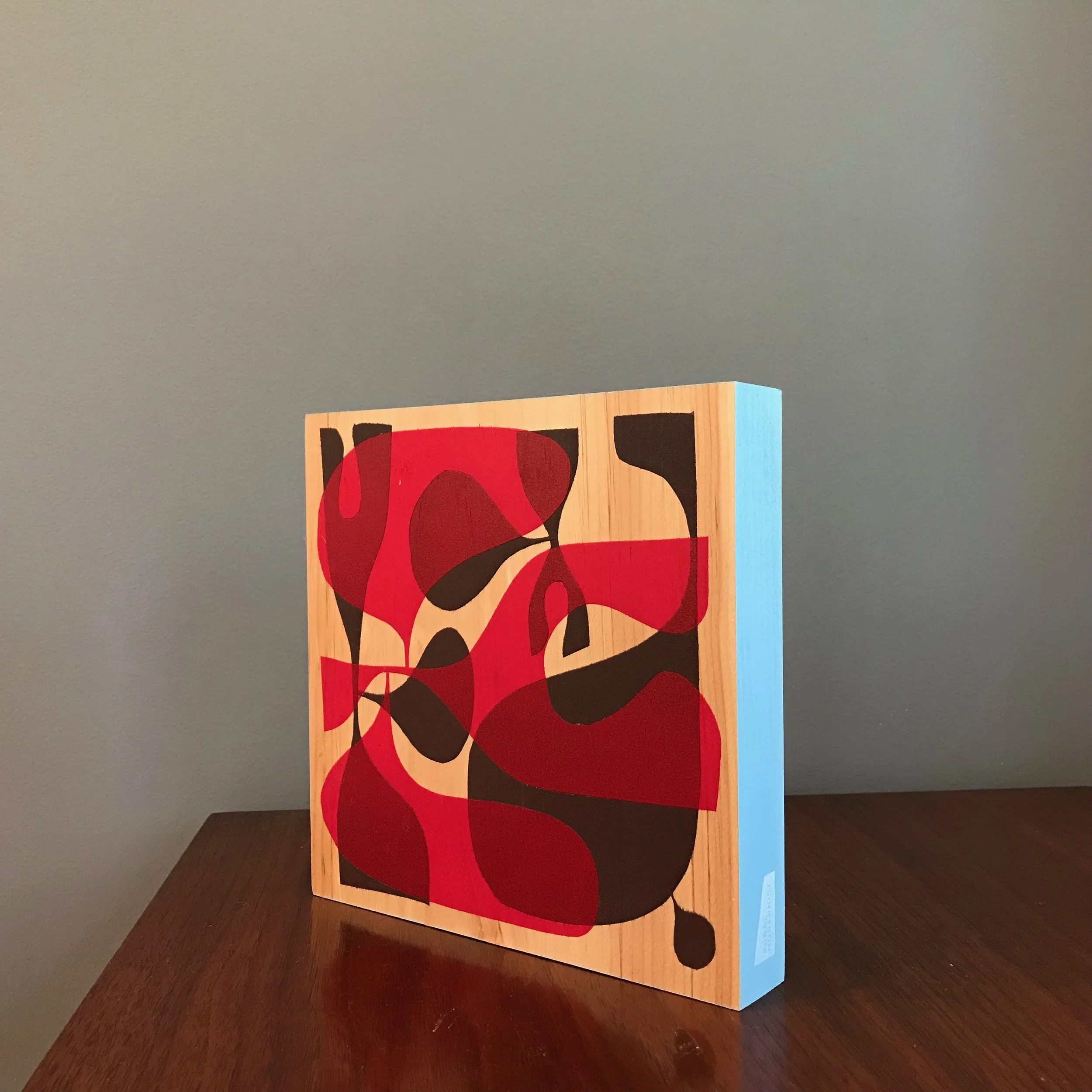 small painting with rocket red and black shapes and a baby blue edge