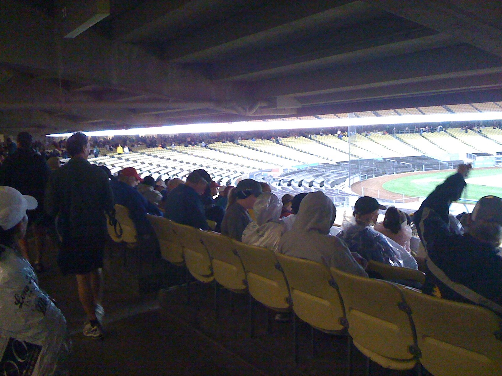  Runners at Dodgers Stadium getting out of the rain by sitting in the bleachers as they wait for the start of the marathon.  
