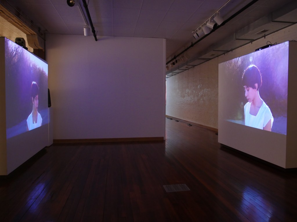 A two-channel video installation shows El Paso resident Aurore Tarango walking in the dry riverbed of the Rio Grande. Image courtesy of the artists.