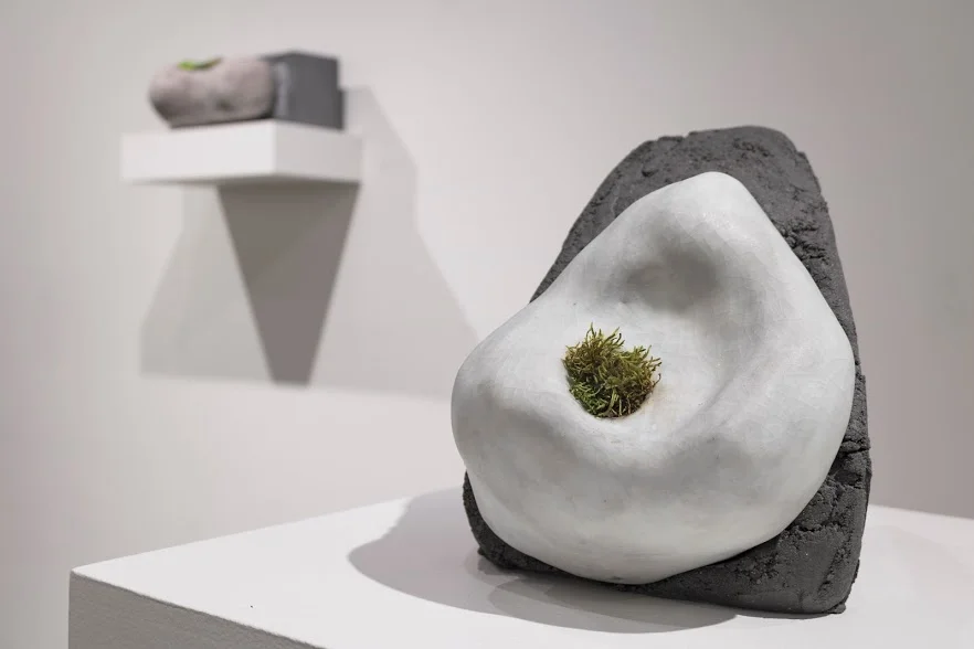 Laura Primozic, Microenvironments 2 , concrete, earthenware, moss. A tuft of green emerges from a ceramic figure on a concrete block.Image courtesy of Lucas Stiegman.