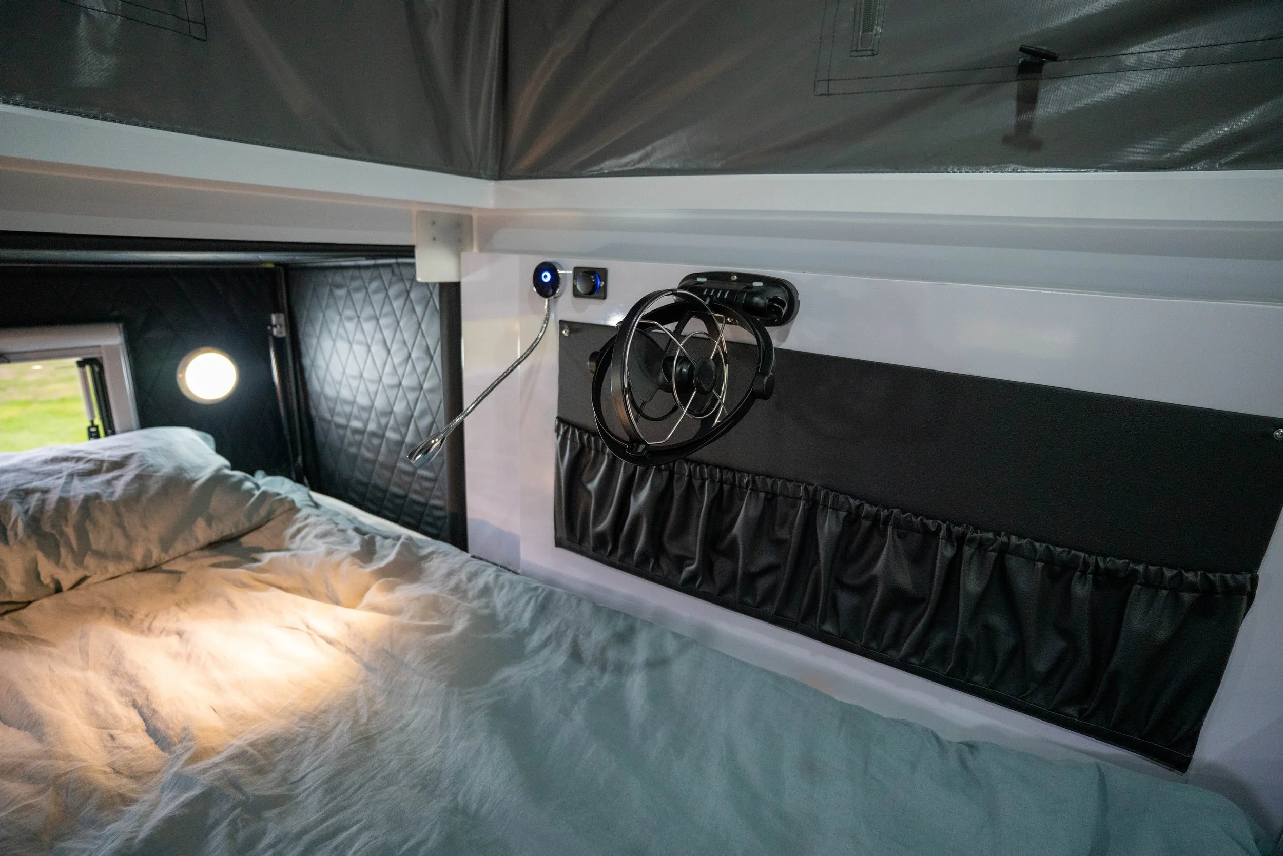 Interior of a bedroom with a bed, window, and wall-mounted fan.