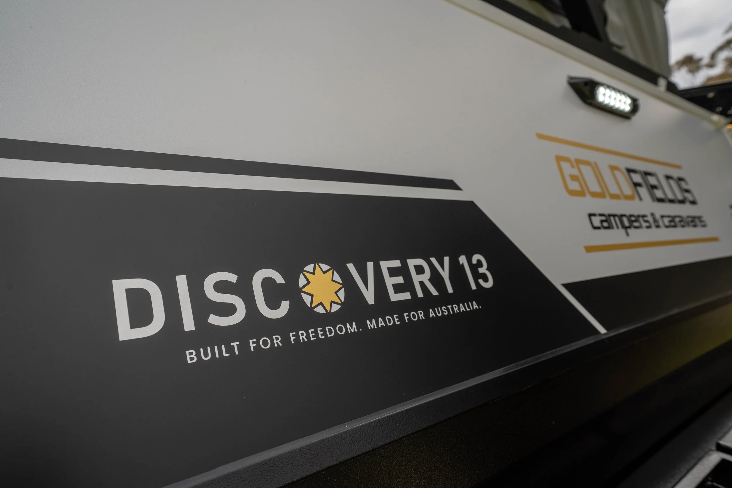 Close-up photo of a phone or printer screen displaying a sticker with the words 'Discover' and 'Built for Freedom. Made for Australia.' and a star logo, with a black and white background design.