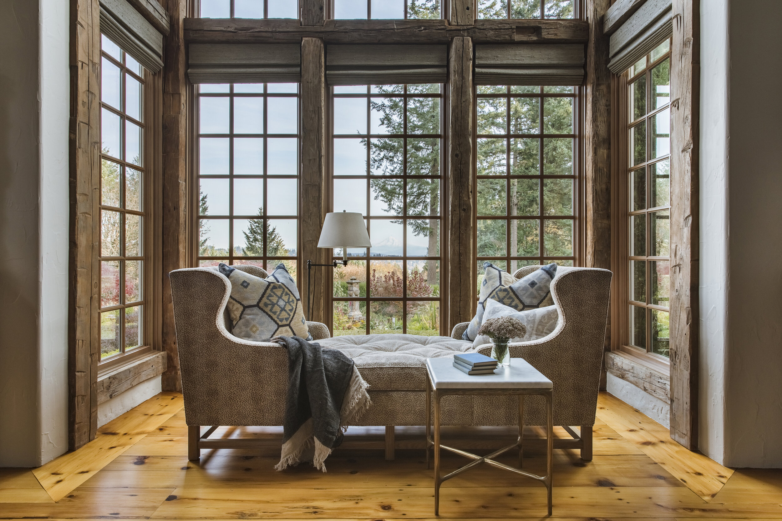  A double-wingback chaise anchors the living room’s double-height bay window, while built-in shelving along an opposite wall frames the new library space. “This room was so big, but they only used a small portion of it,” Nesen says. “We really wanted