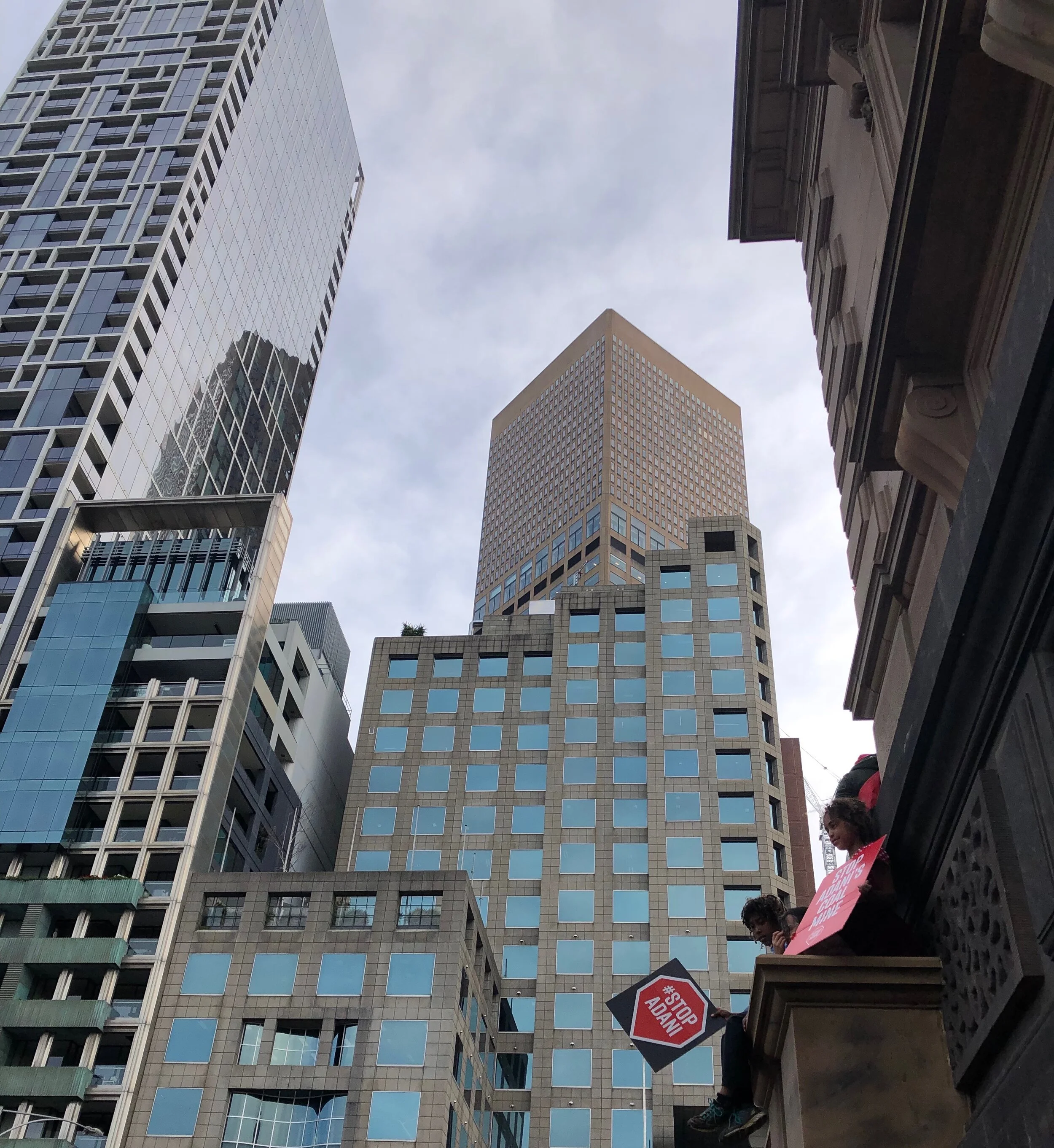Children overlook the rally and hold ‘#Stop Adani’ signs. Photograph by Coral Huckstep