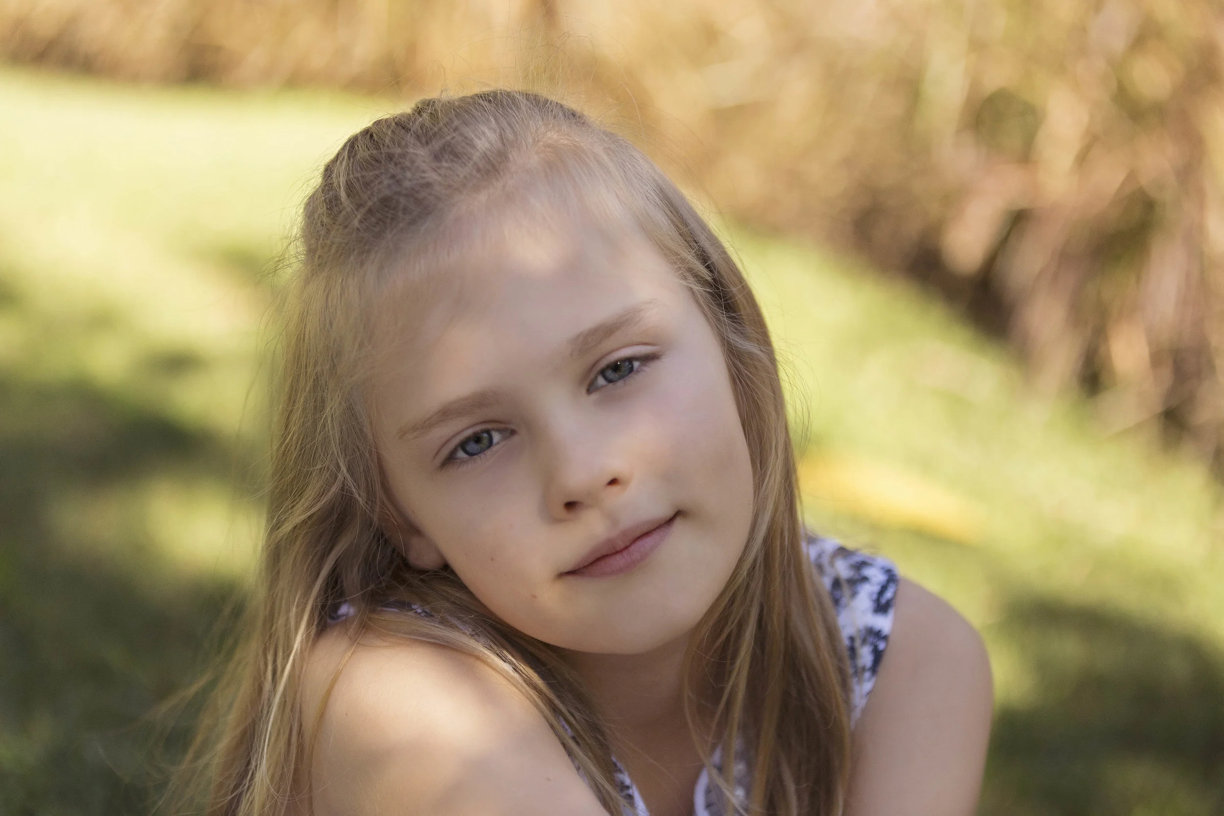 A sweet young girl with lovely long blonde hair and stunning blue eyes in the park