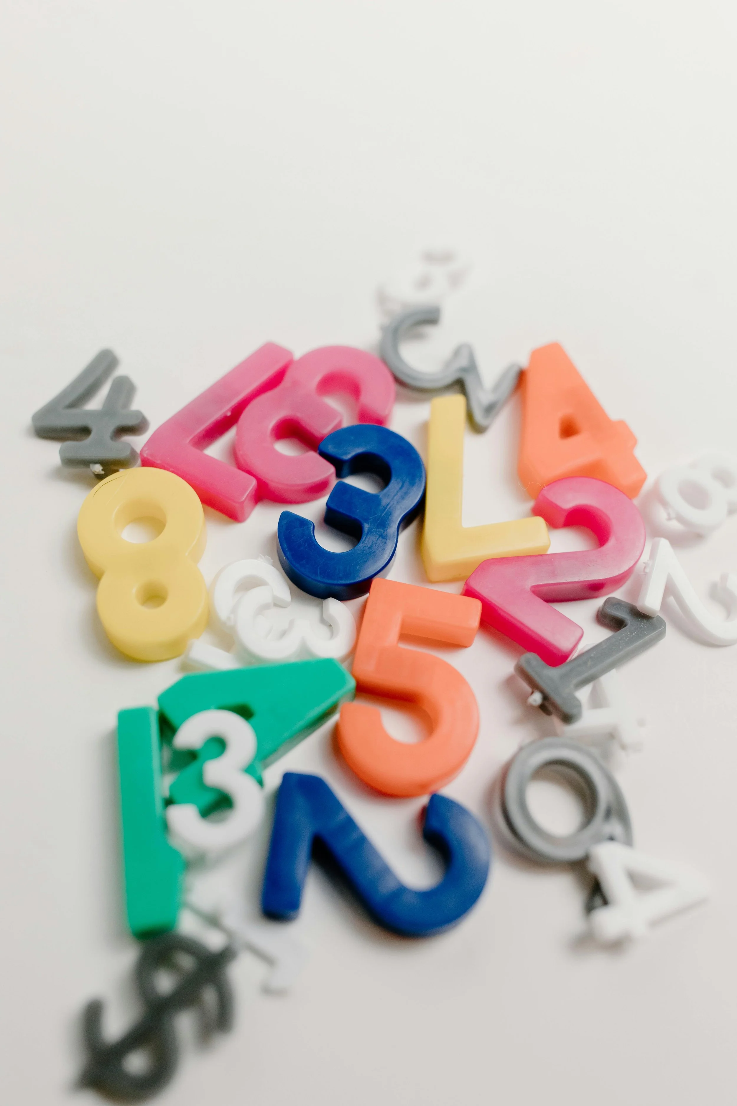 Colorful plastic numbers scattered on a white surface, with some numbers visible and others partially out of view.
