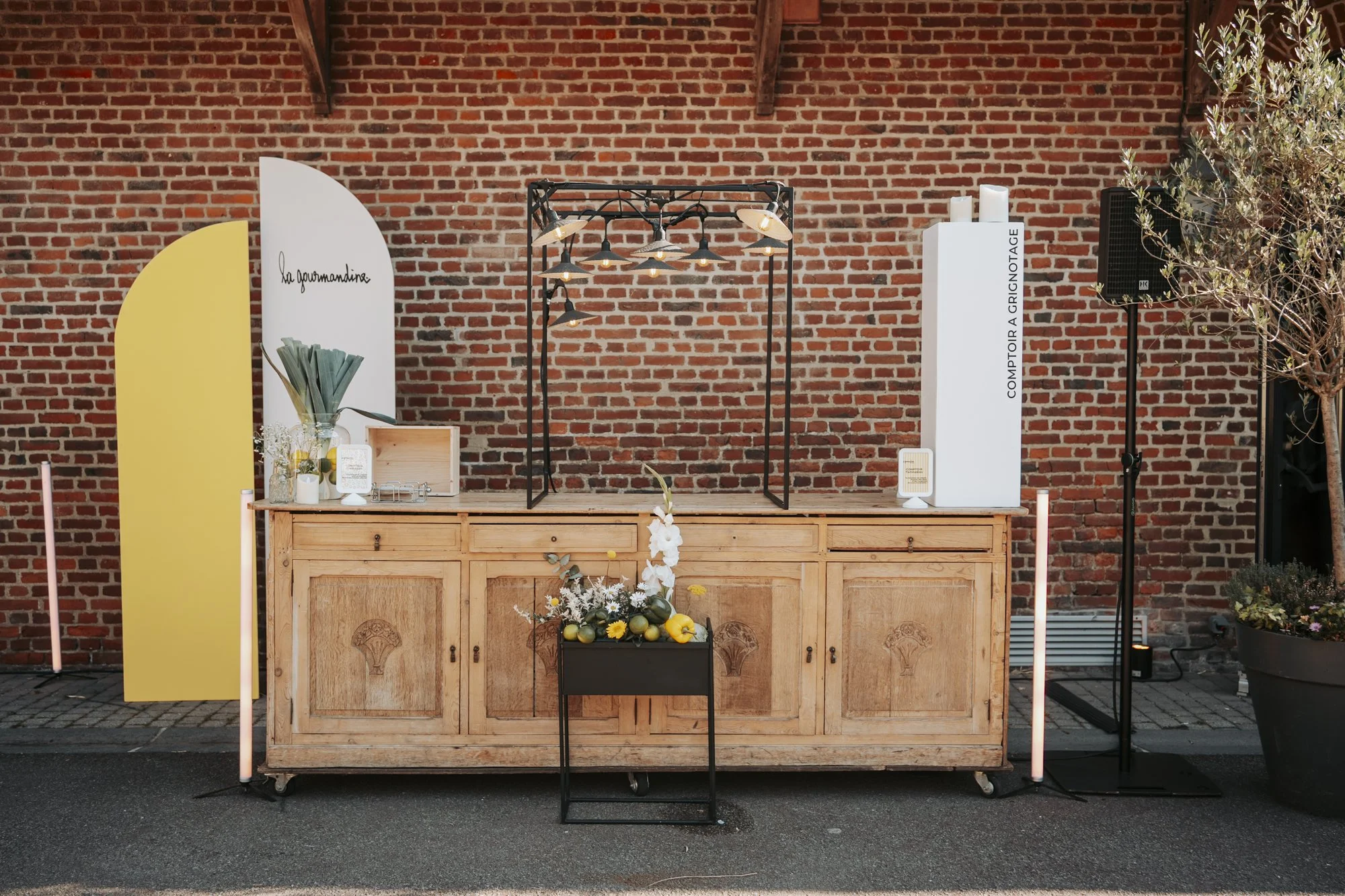 Buffet en bois dressé devant un mur de briques, scénographie d'événement