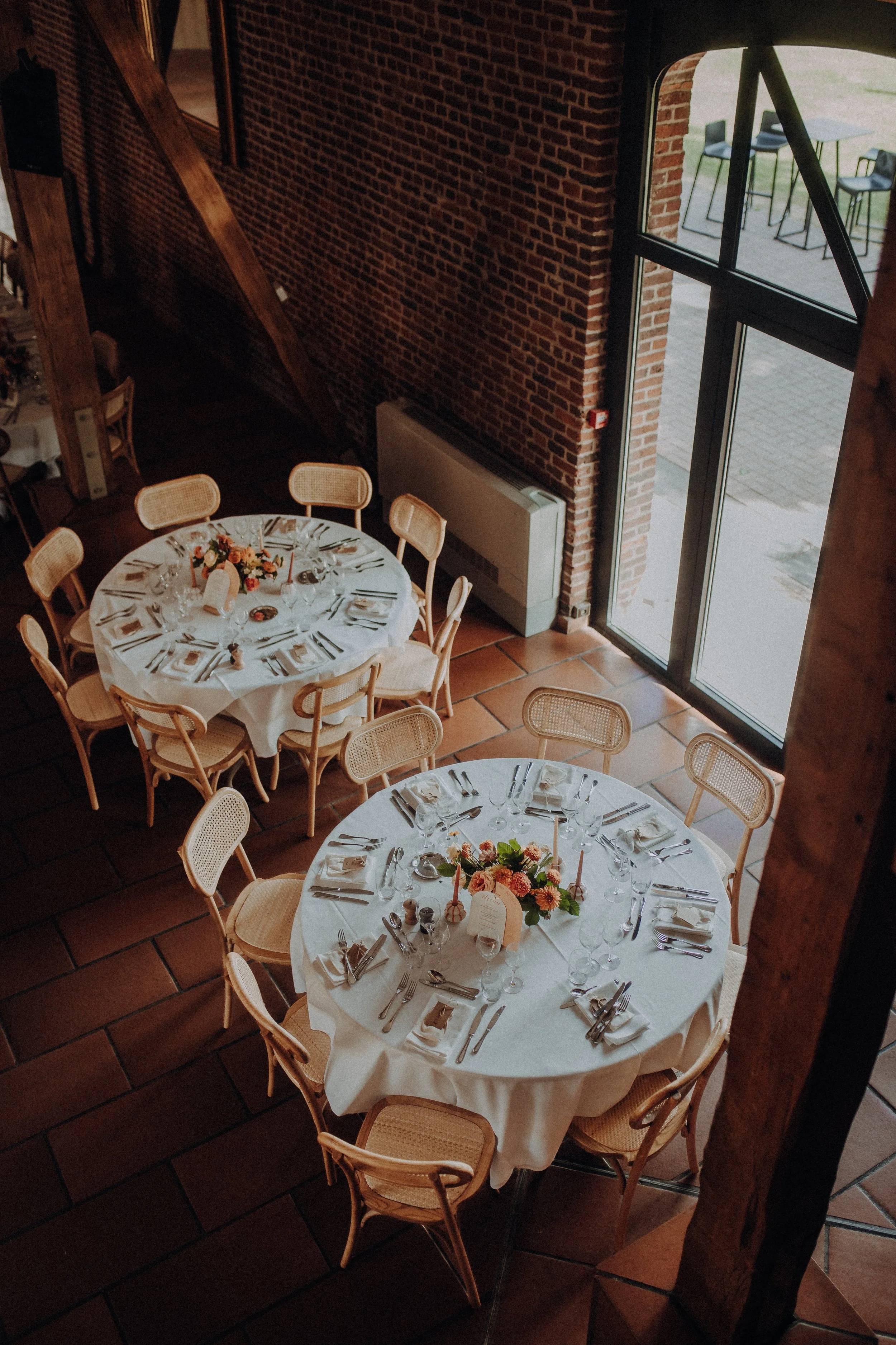 Tables rondes dressées dans la Grange pour un mariage au Clos de la Source
