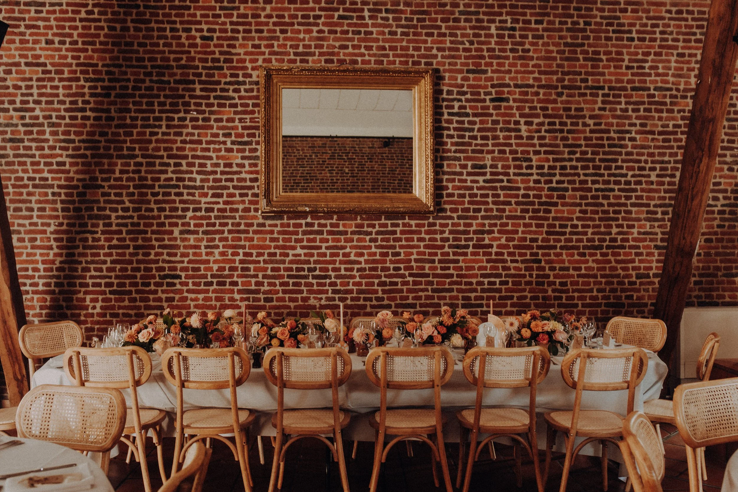 Table d’honneur d’un mariage devant un mur en briques au Clos de la Source