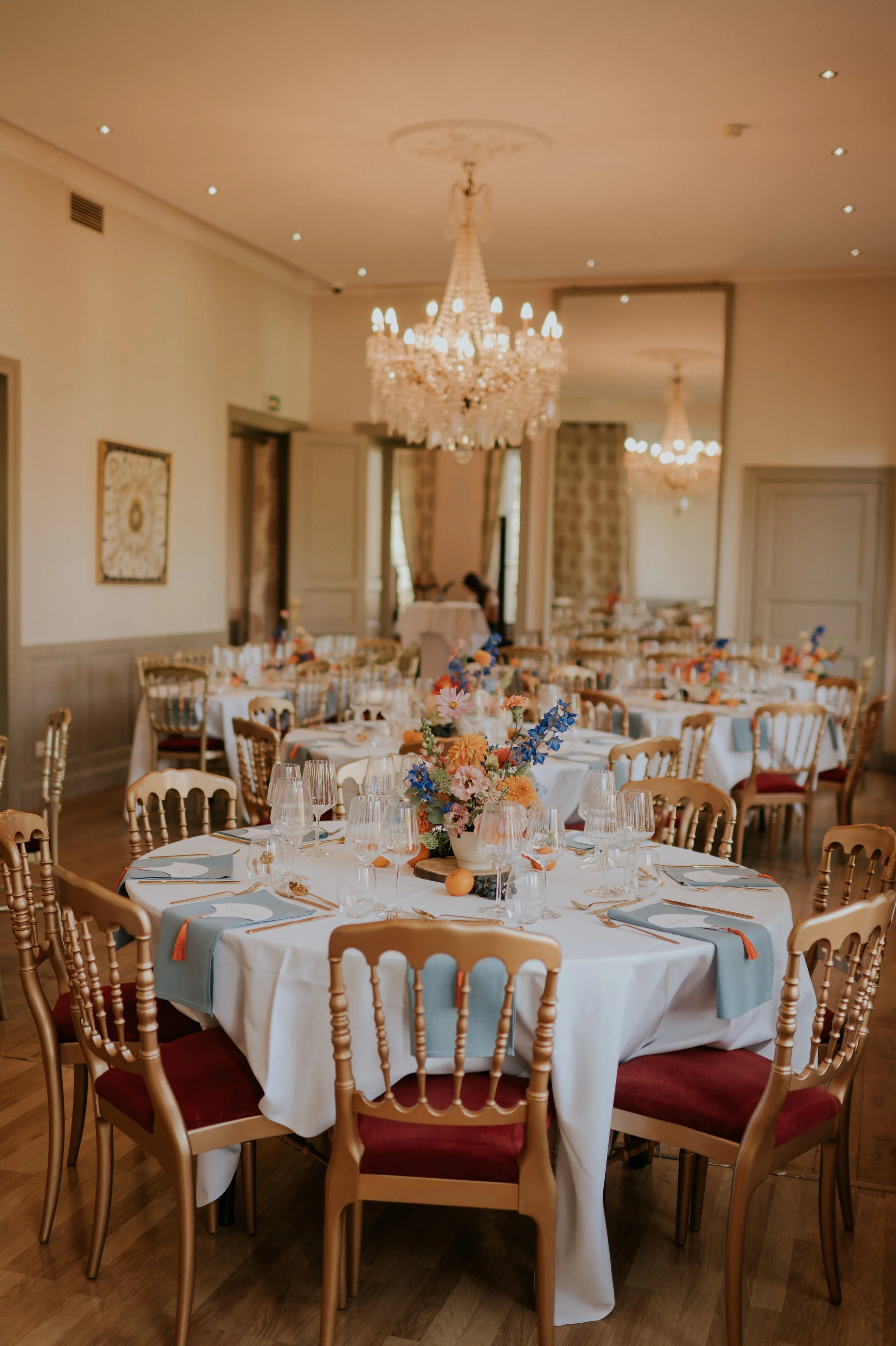 Tables rondes et lustres en cristal dans un salon du Château d’Aubry