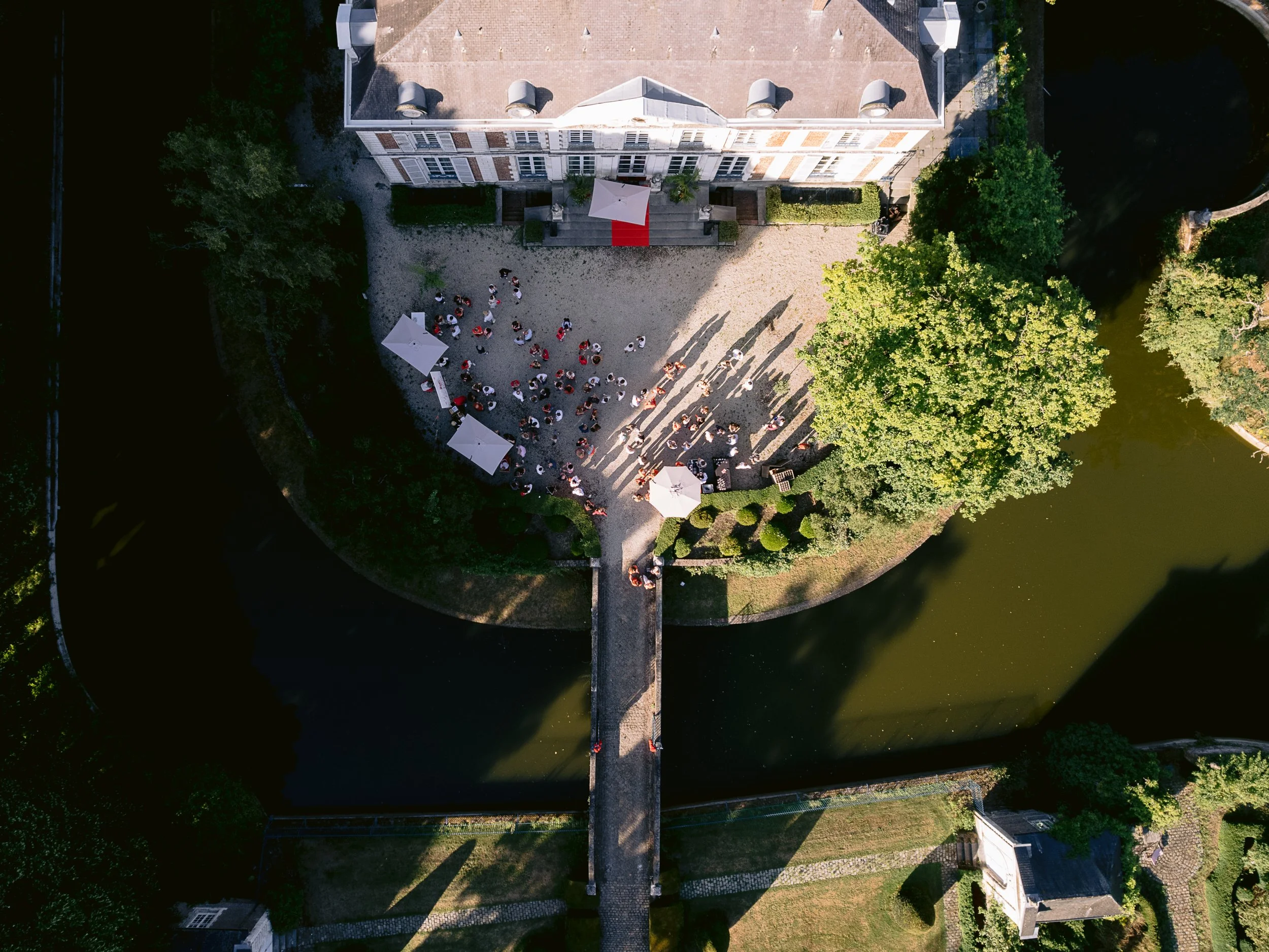 Vue aérienne d’une réception dans la cour du Château du Vert-Bois, entourée de douves