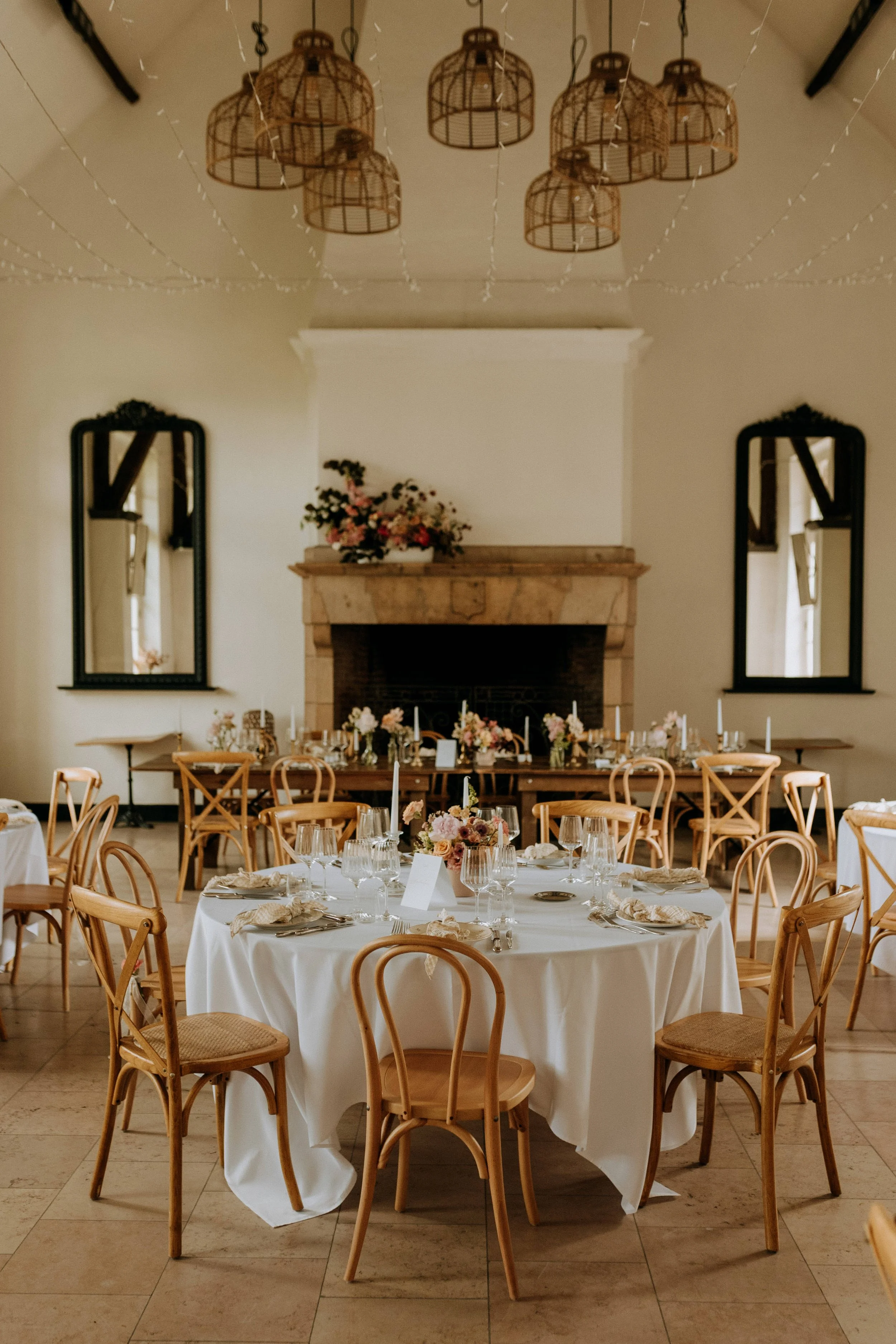 Salle du Domaine d’Achelles dressée pour un dîner de mariage, devant la cheminée