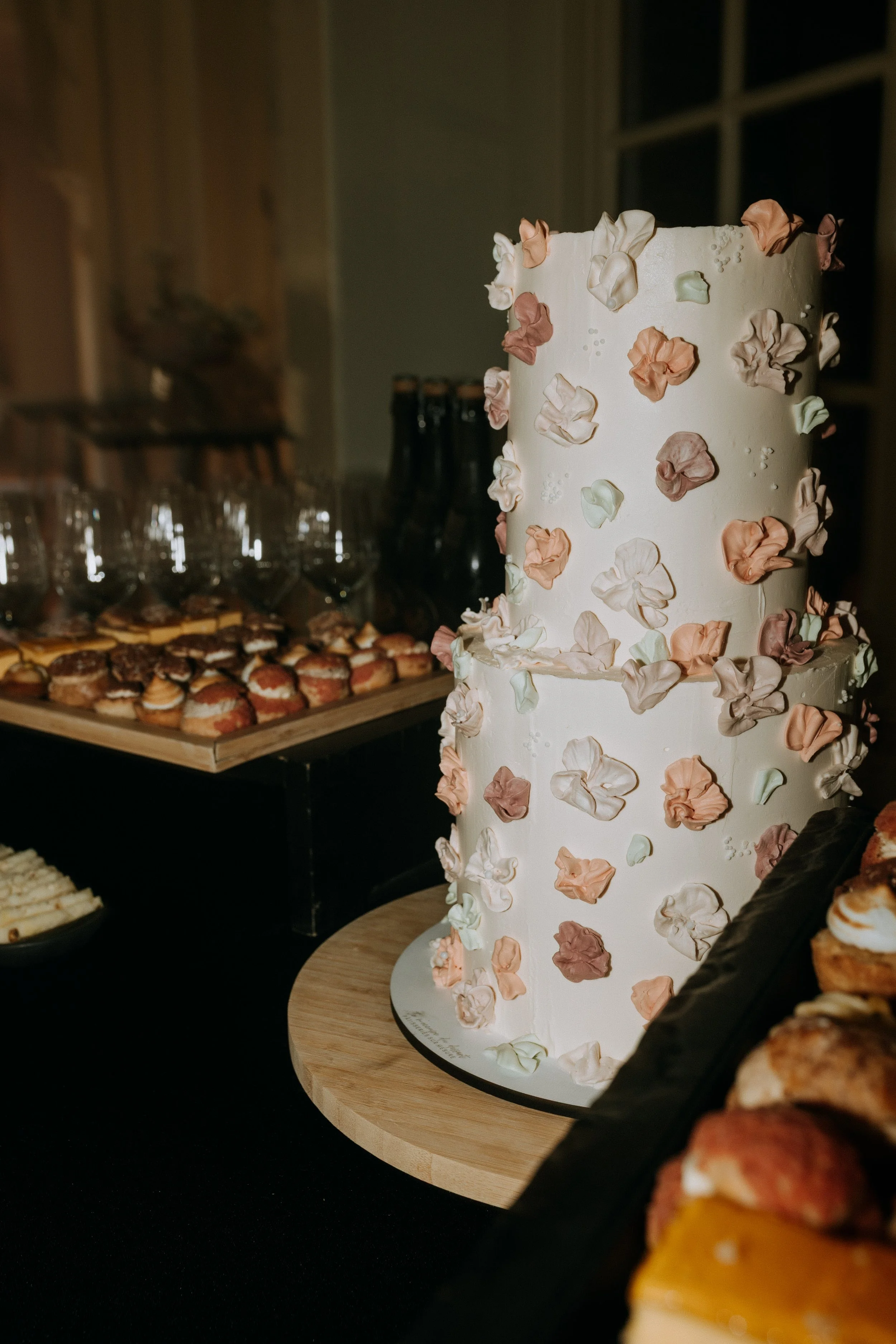 Gâteau de mariage décoré de pétales et buffet de desserts au Domaine d’Achelles